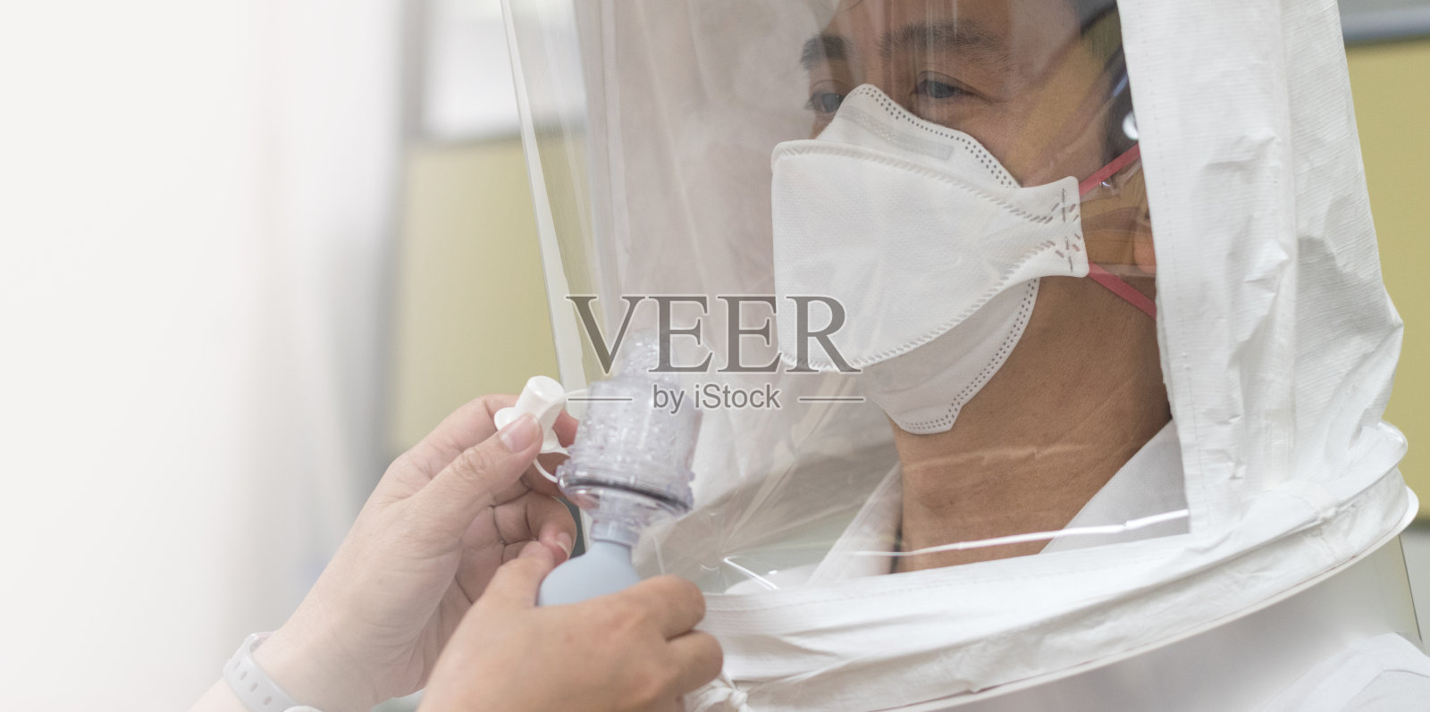 为COVID-19准备的呼吸器适配测试。亚洲男子用N-95外科口罩测试呼吸系统，以检查面罩是否适合佩戴。照片摄影图片