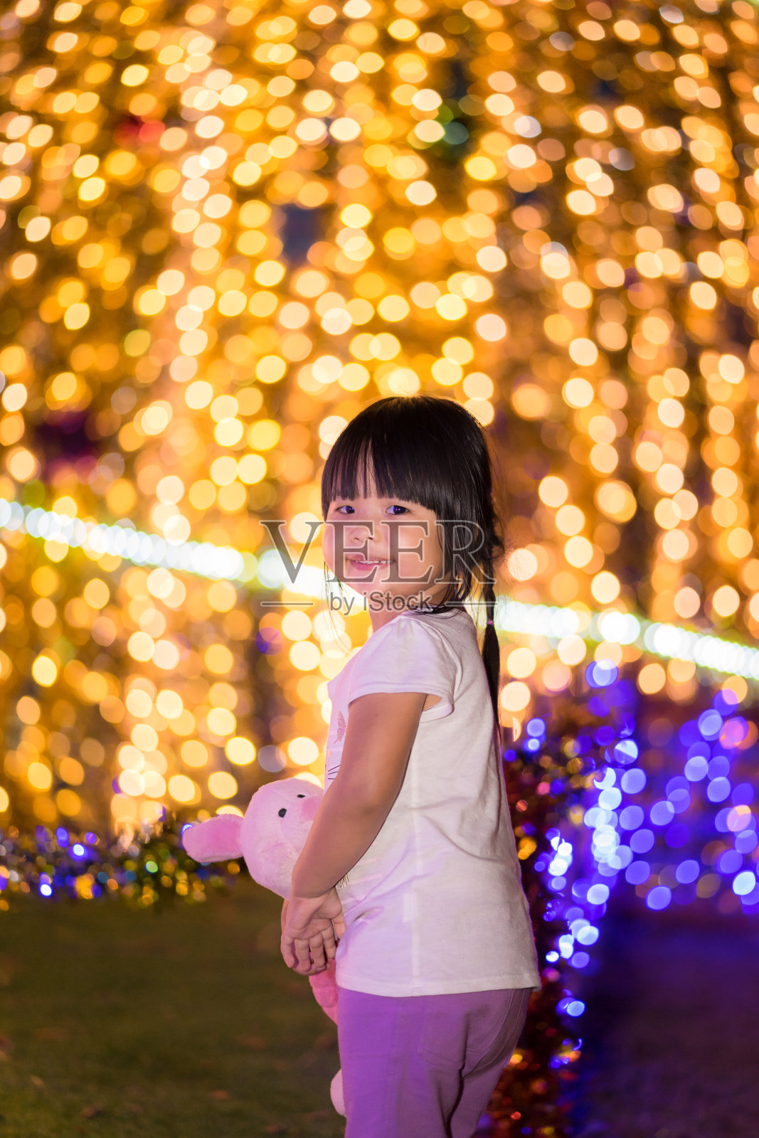 亚洲小女孩拥抱娃娃和散景在圣诞节的背景照片摄影图片