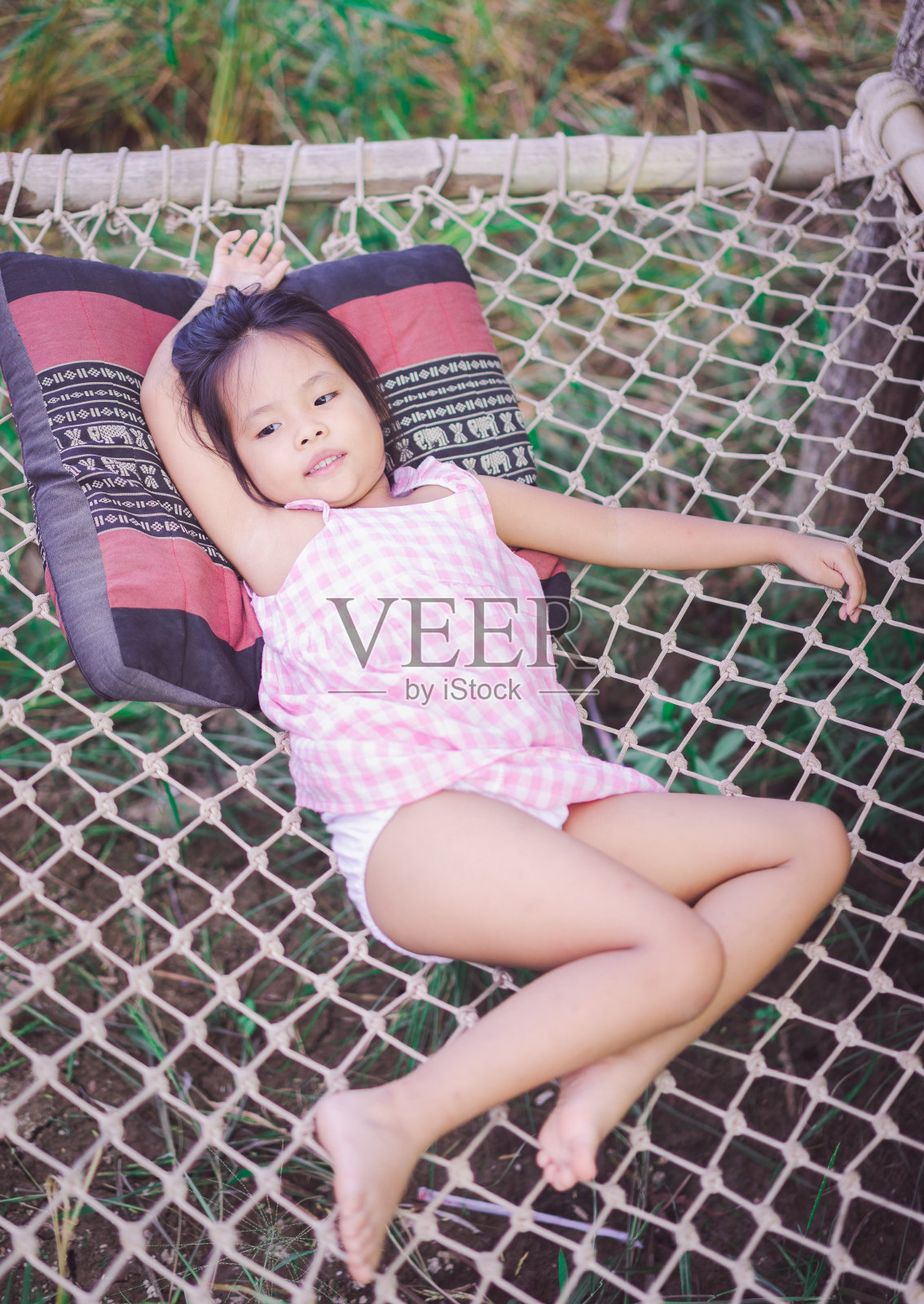 一个亚洲小女孩躺在网球场的长椅上照片摄影图片