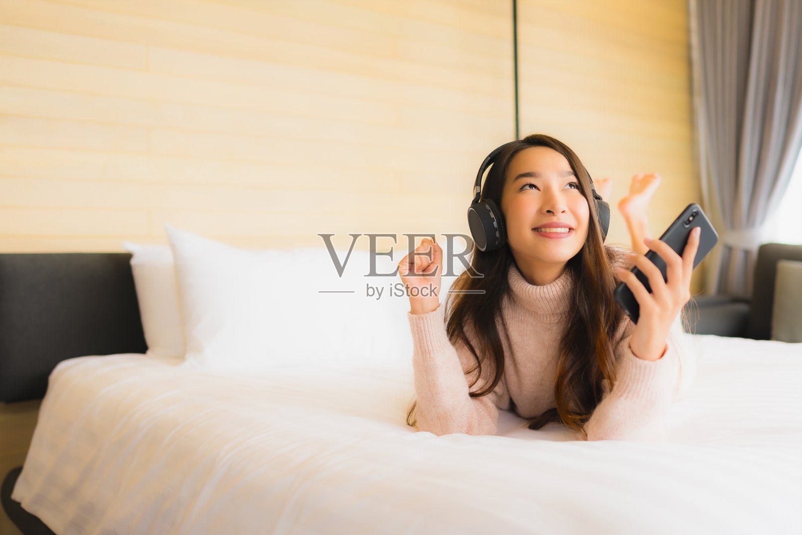 肖像美丽的年轻亚洲女子使用手机与耳机听音乐照片摄影图片