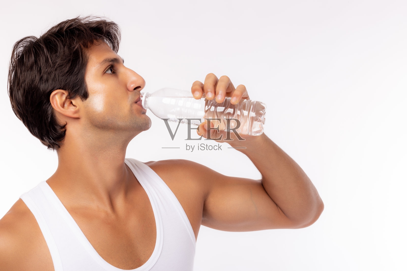 白种人在夏天，炎热的天气喝瓶子里的水。帅气的白人模特手里拿着一个透明的瓶子。肌肉男身体好酷男口渴感觉清爽照片摄影图片
