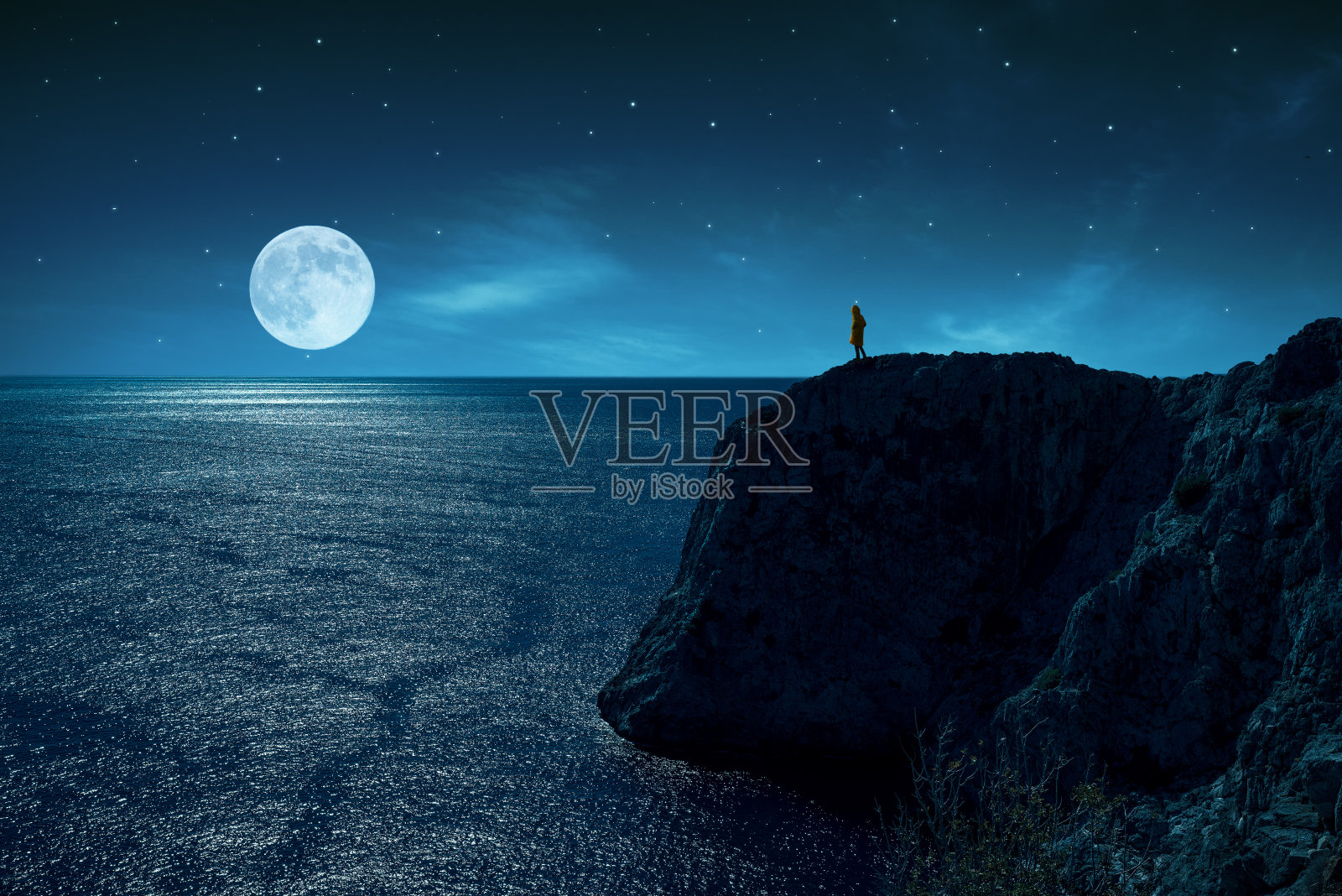 人是站在悬崖边对着大海和满月，在星星和月光下。照片摄影图片