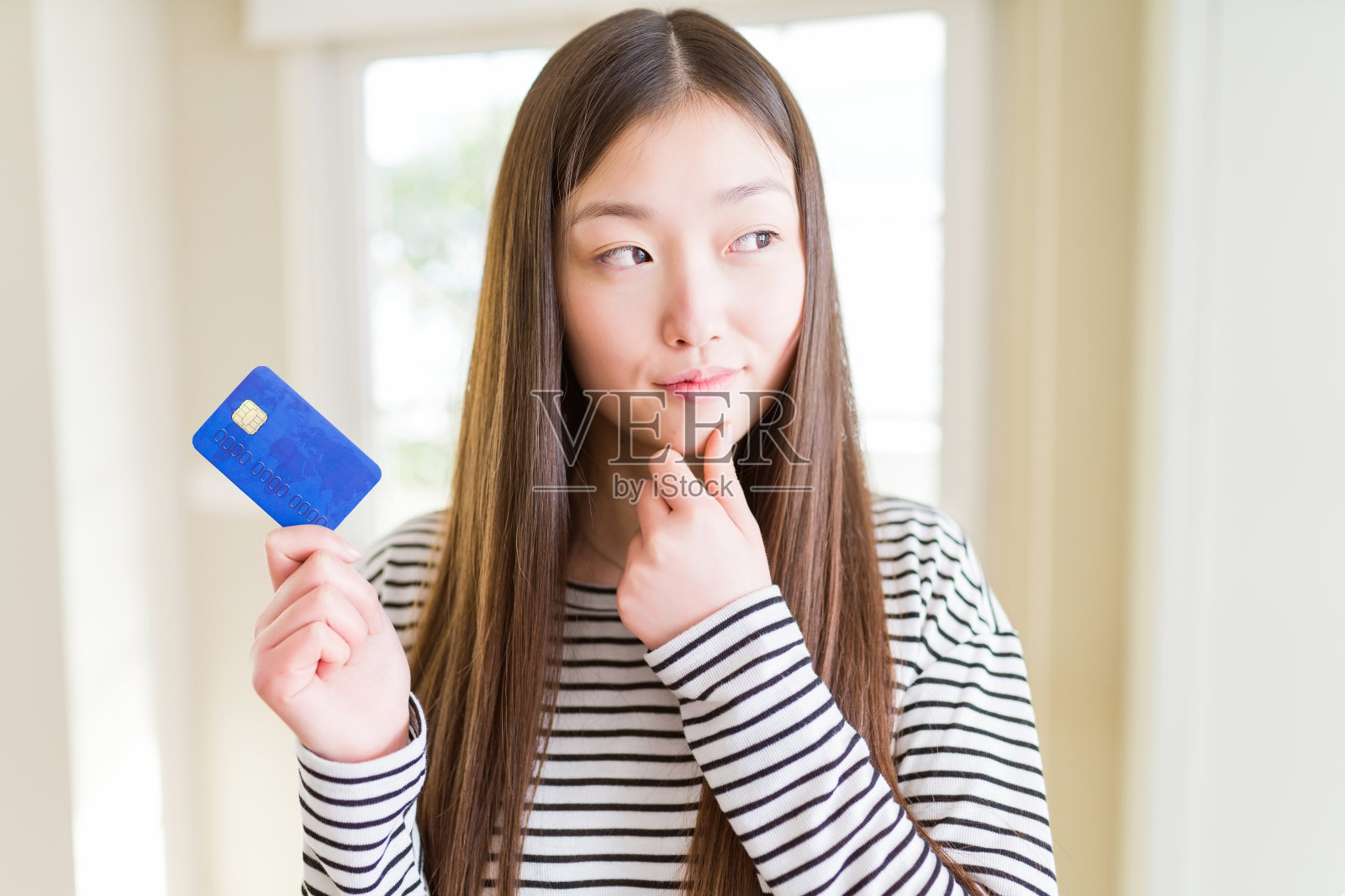 美丽的亚洲女人拿着信用卡严肃的面对思考问题，非常困惑的想法照片摄影图片