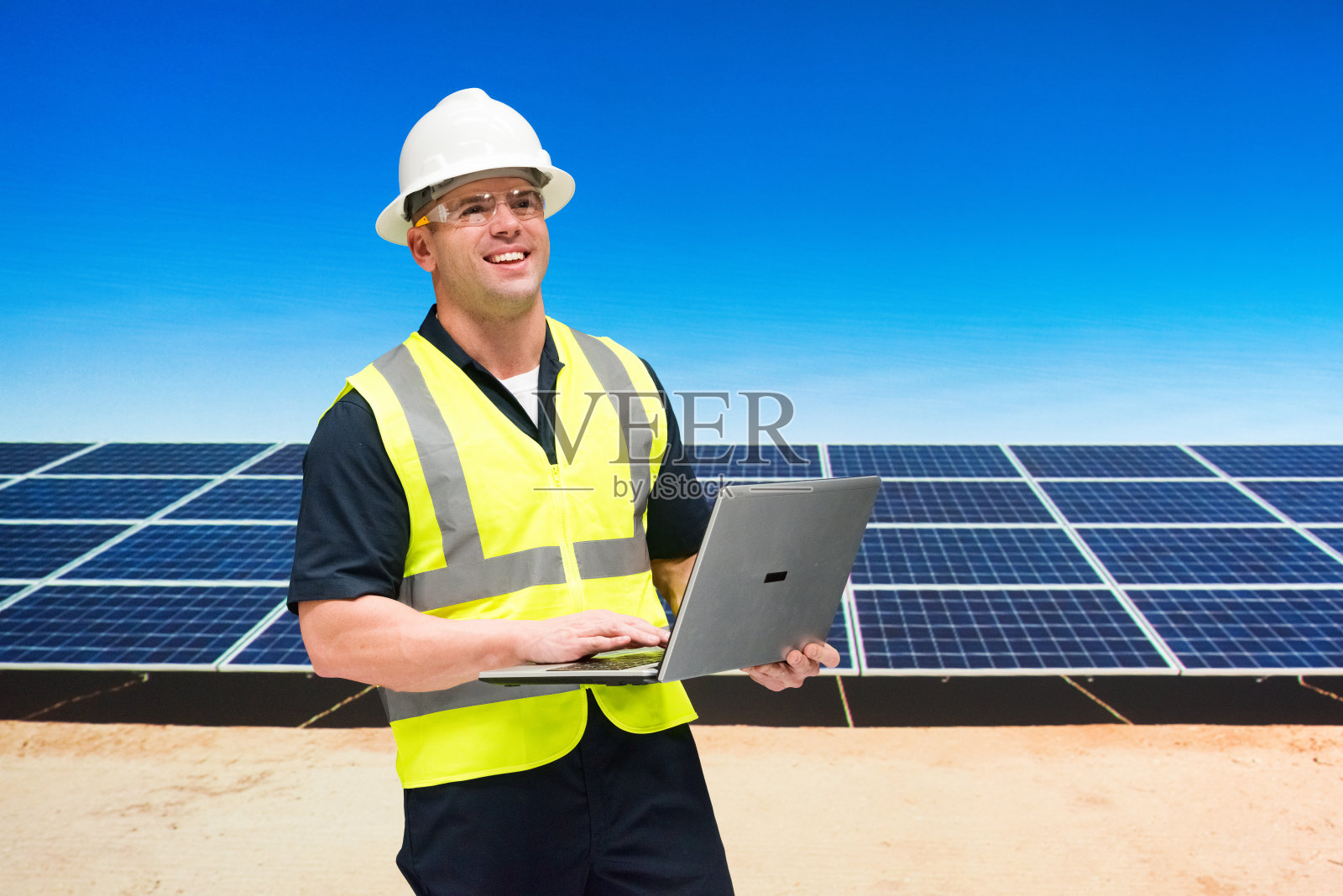 白人男性电工在太阳能发电站，他在户外戴着安全帽，支持可再生能源和使用电脑照片摄影图片