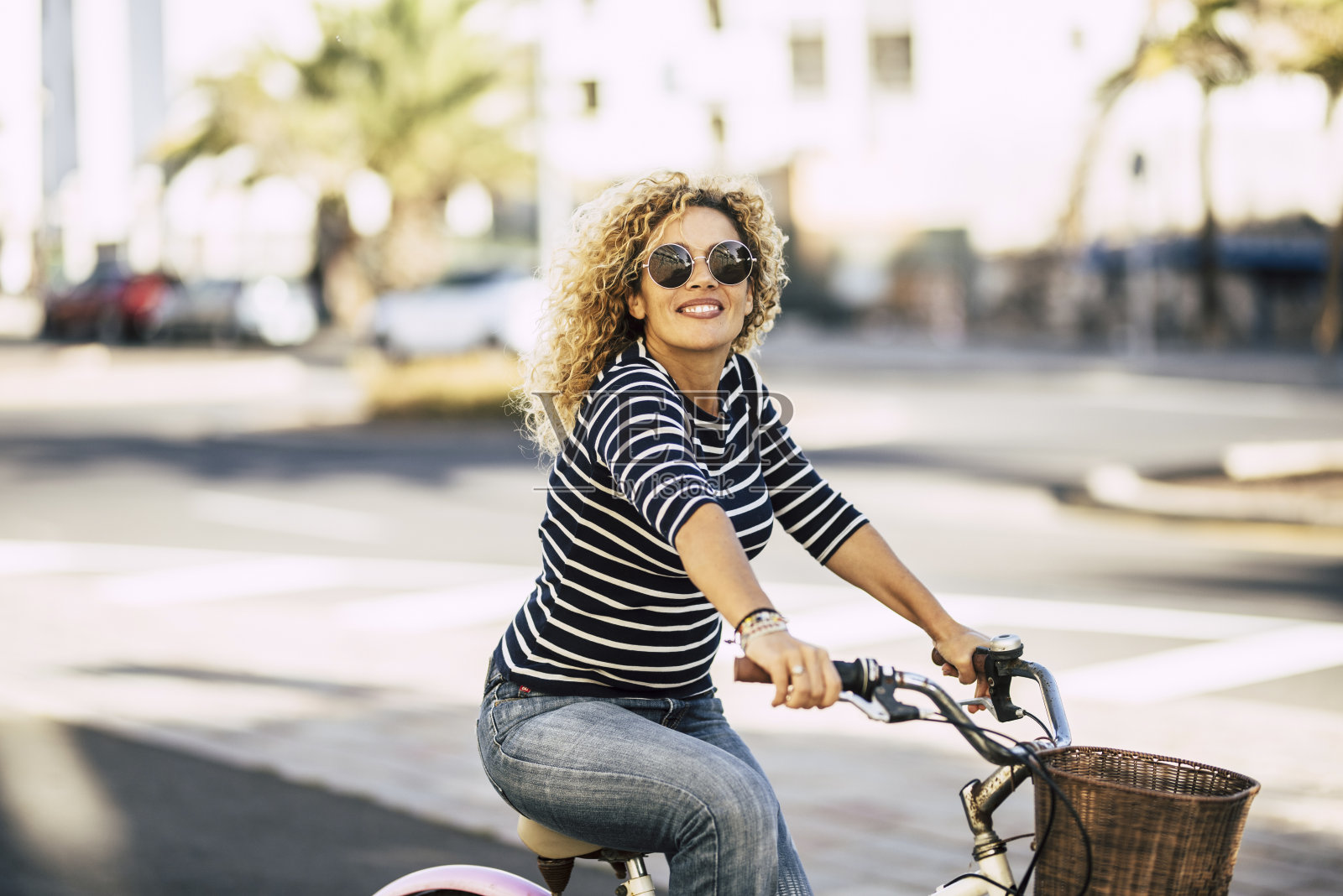 美丽开朗的成年年轻女子在阳光明媚的城市户外休闲活动骑自行车-快乐的人肖像-时尚的女性在外面玩照片摄影图片