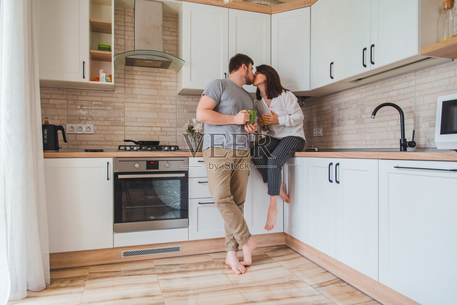 年轻夫妇在厨房喝茶时接吻照片摄影图片