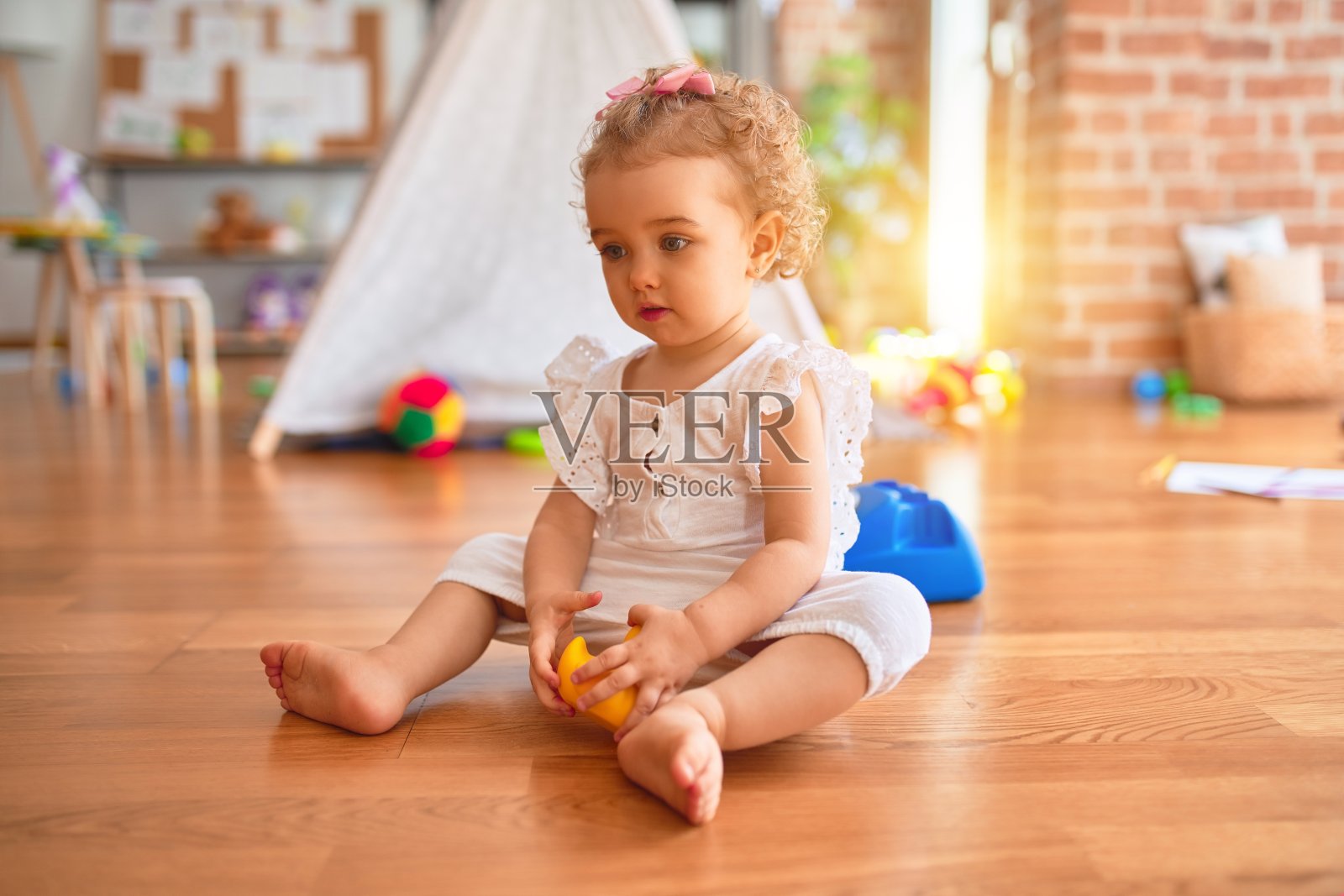 美丽的白人婴儿玩玩具在彩色的游戏室。在幼儿园快乐和好玩。照片摄影图片