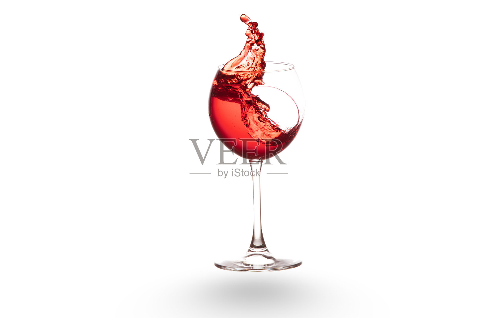 红酒从酒杯里溅出来，孤立在白葡萄酒上照片摄影图片