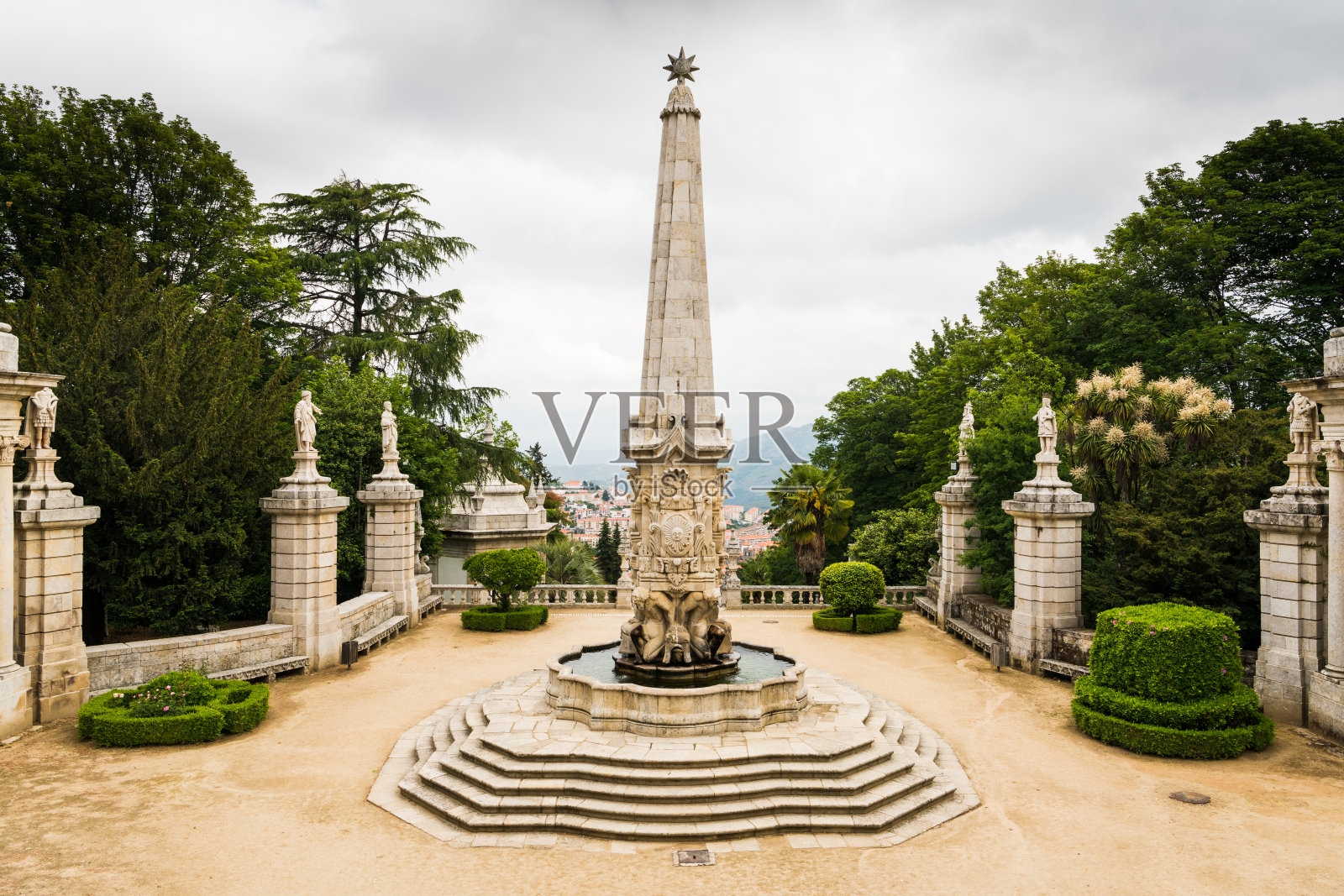 美丽的庭院，一个华丽的喷泉和方尖碑周围的古典雕像和绿色植物高于一个欧洲村庄照片摄影图片