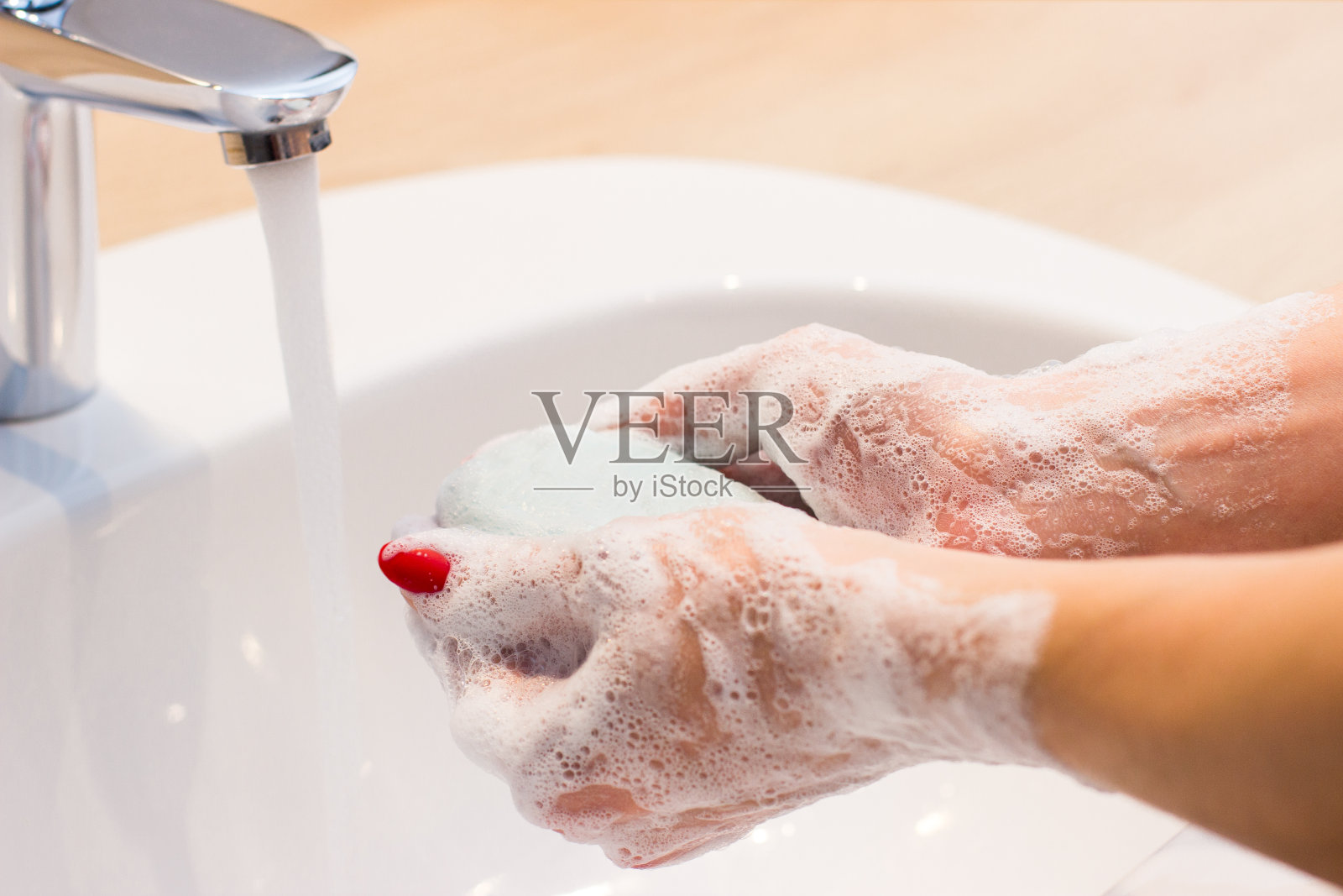 卫生观念和病毒预防。那位妇女在水龙头下用肥皂和水洗手。照片摄影图片