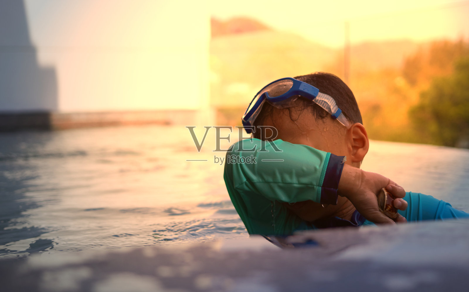 男孩在泳池边玩水，在阳光下游泳，选择性聚焦照片摄影图片