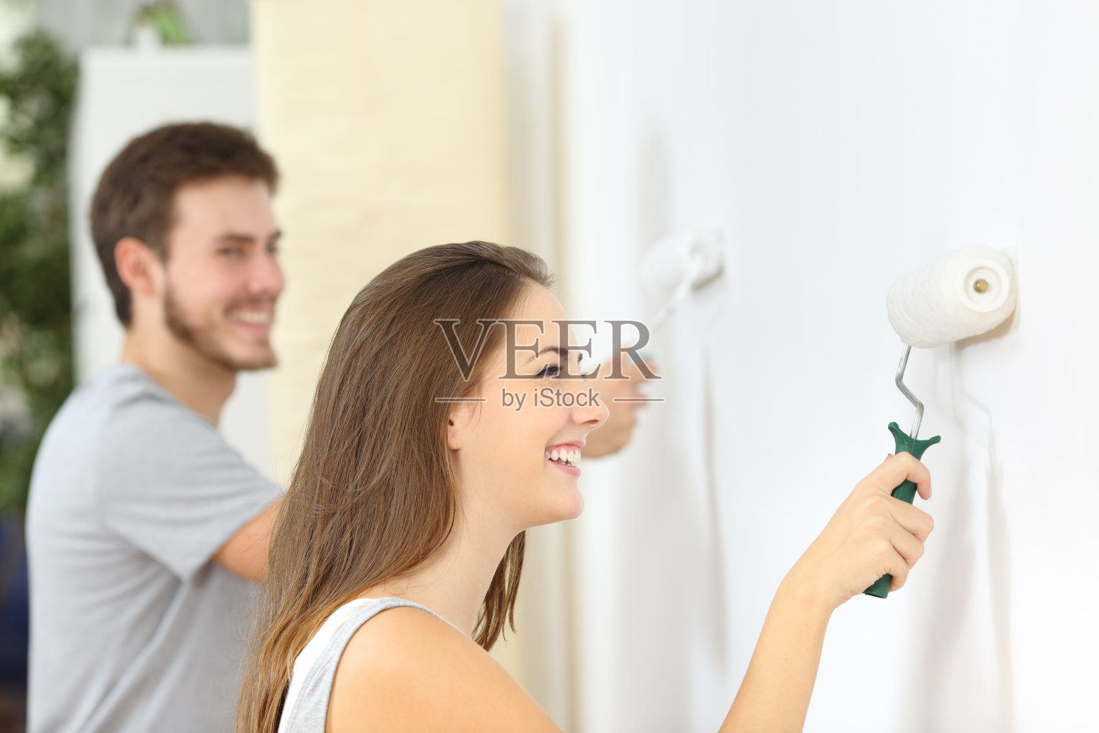 幸福的夫妇在家里用油漆滚筒刷墙照片摄影图片