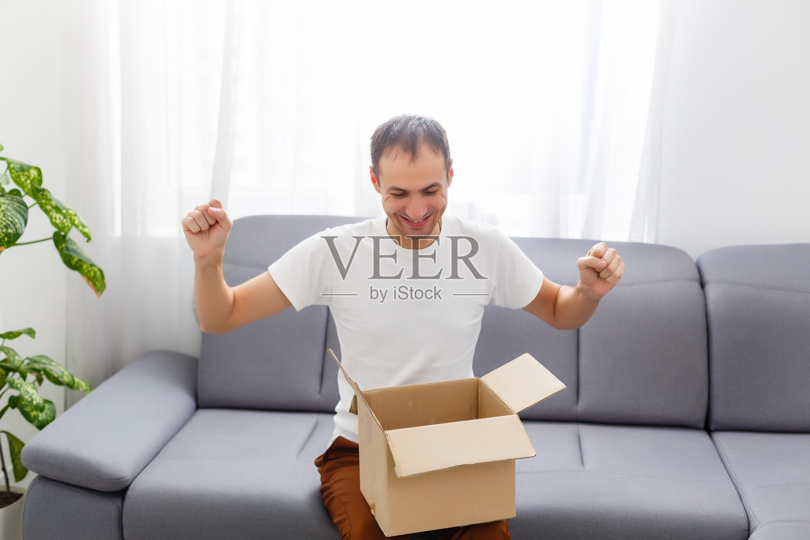 公寓里一个开着盒子的快乐男人照片摄影图片