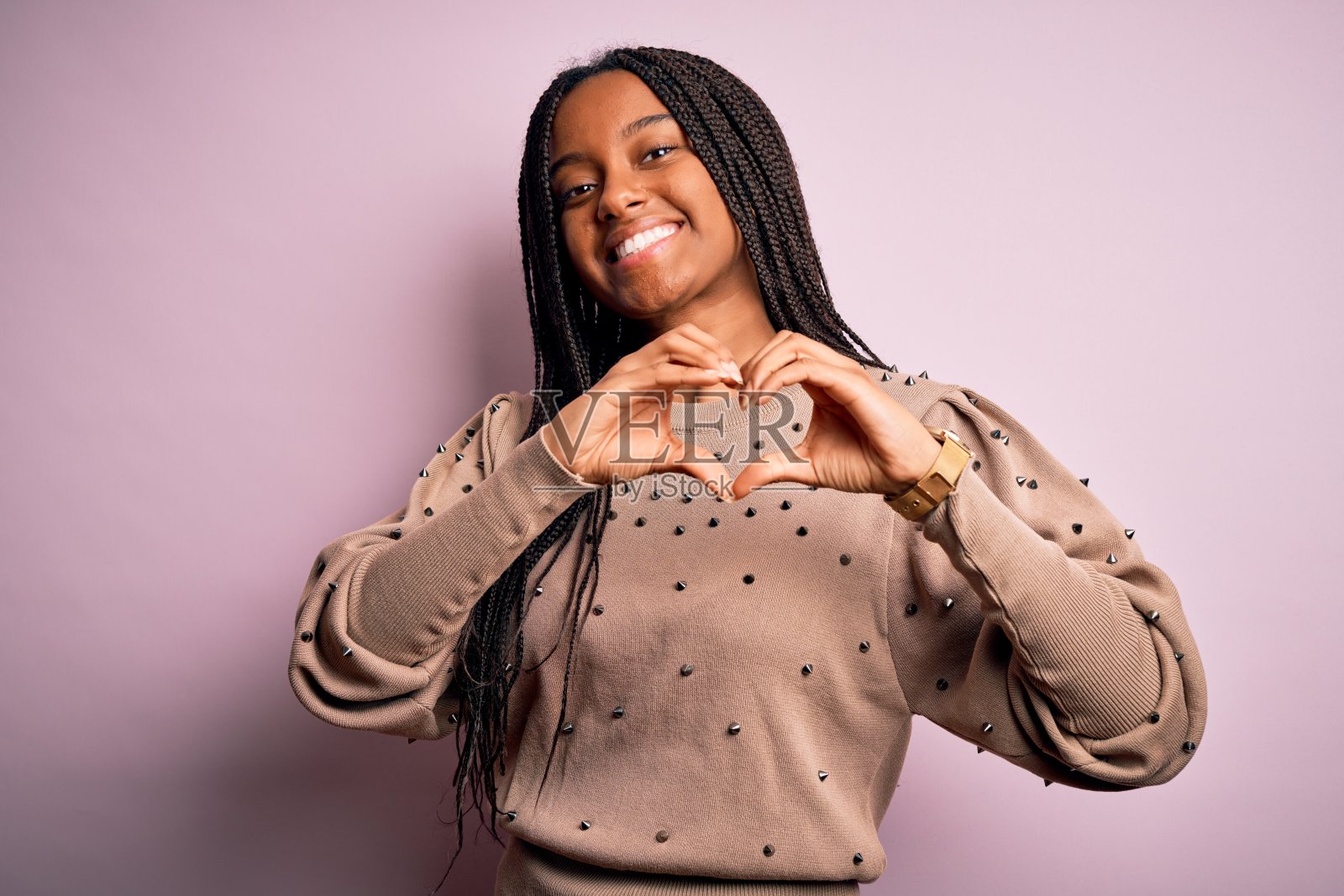 年轻的非洲裔美国妇女穿着时尚毛衣在粉红色孤立的背景微笑在爱显示心形符号和形状的手。浪漫的概念。照片摄影图片