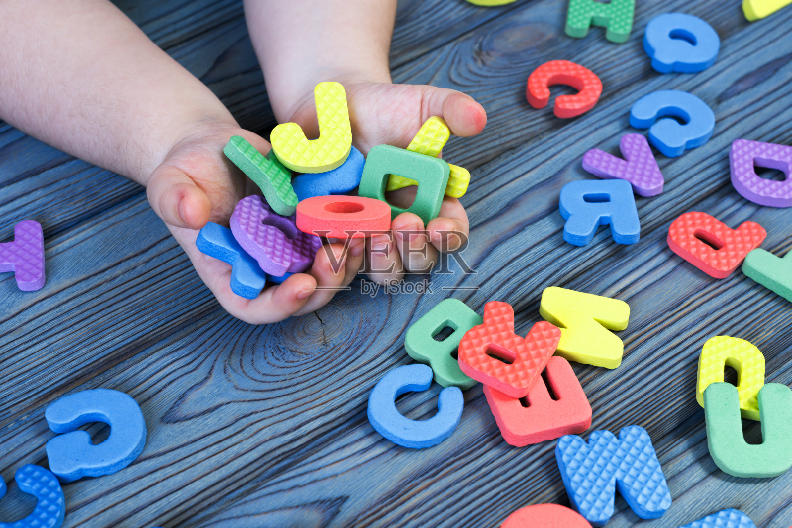 字母的英文字母在一个孩子的手中木制的背景上。照片摄影图片