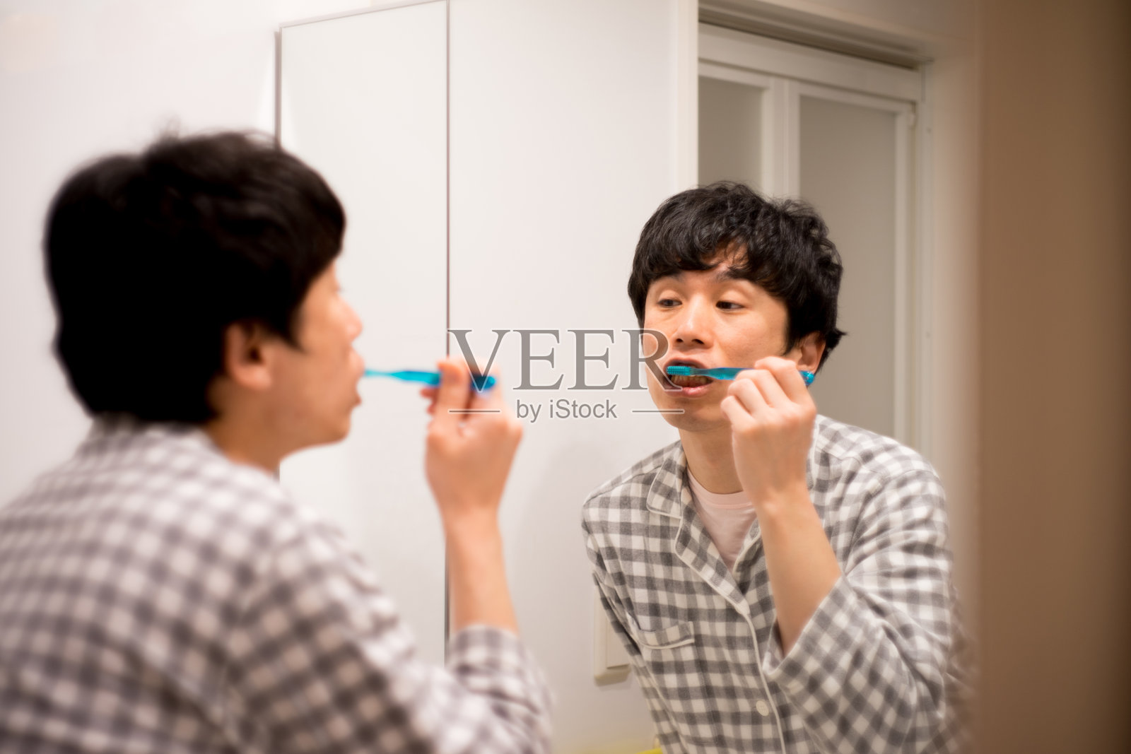 穿着睡衣的日本男人在家里的浴室里戴着牙刷和漱口水照片摄影图片