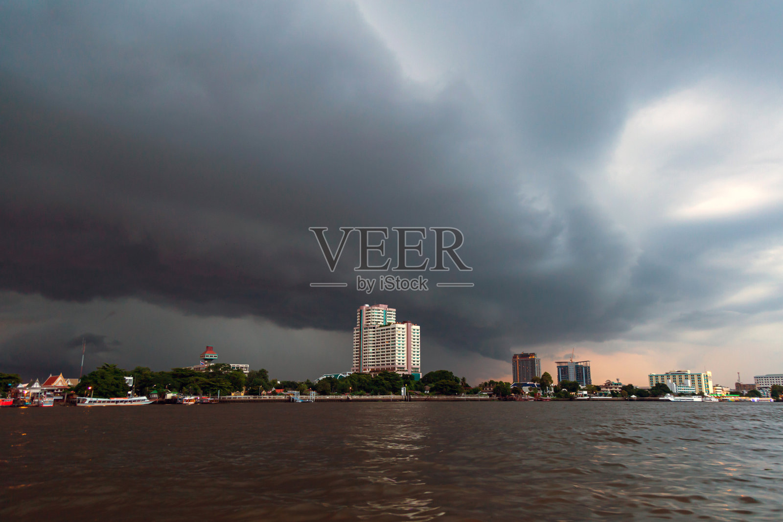 城市景观河视图与黑色的雨云在雨即将来临之前城市建筑。照片摄影图片