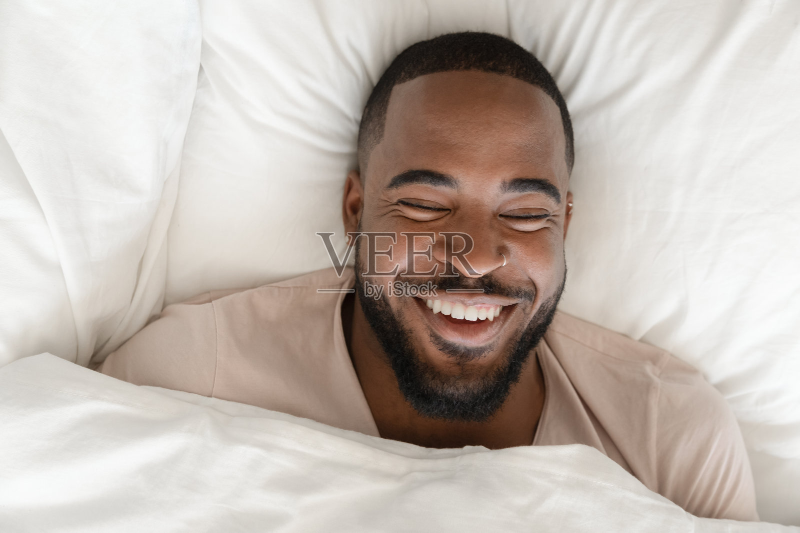 从上面看，一个英俊的非洲男人躺在床上笑了照片摄影图片