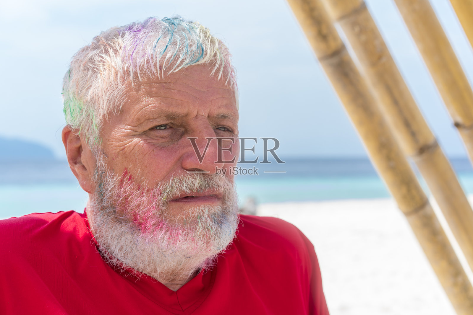 在马来西亚婆罗洲的沙滩和海洋上，一名染着头发的老人的肖像。照片摄影图片