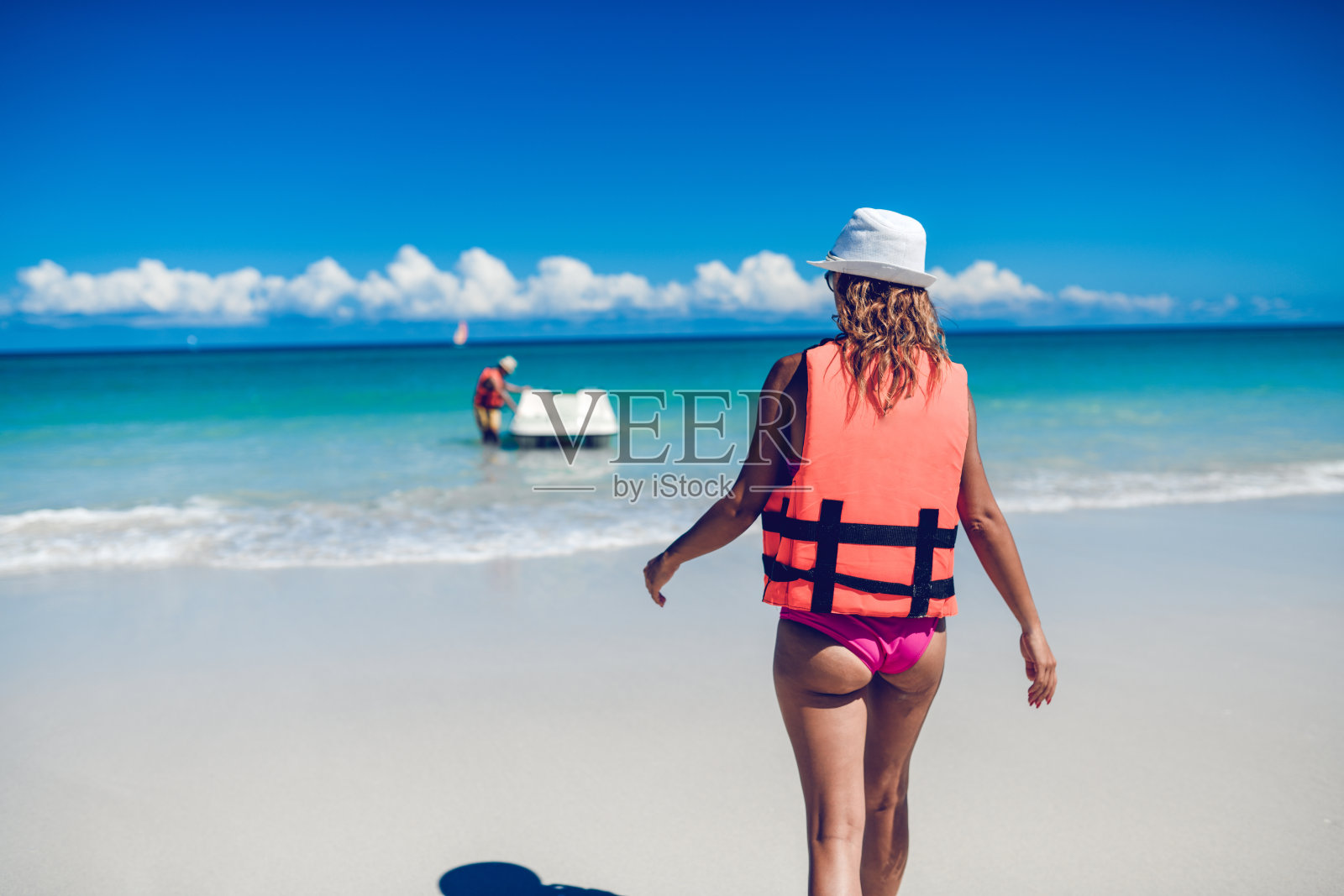 在海滩上，一名女子骑着脚踏船走向一名男子照片摄影图片