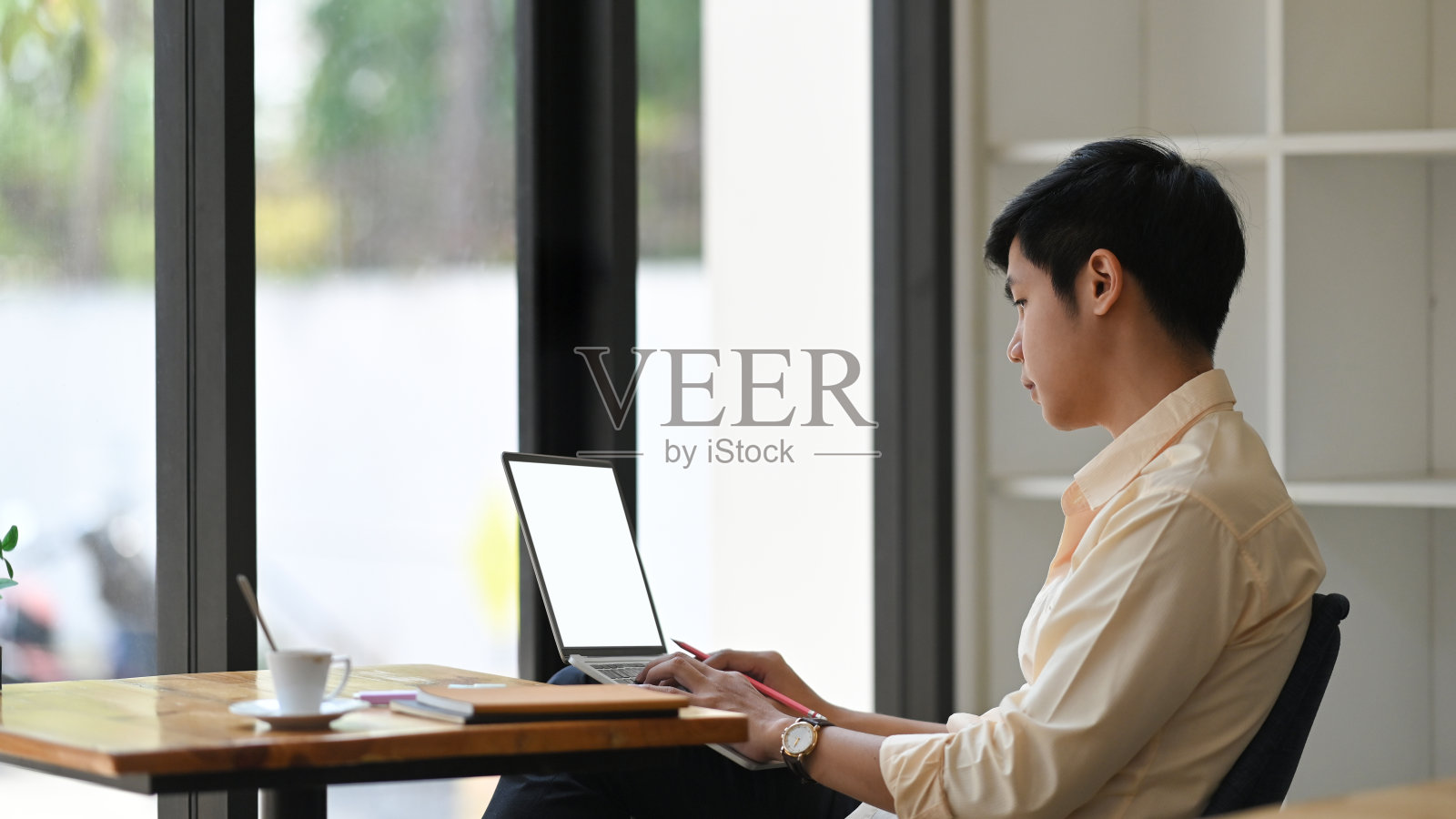 一个做会计的人，在膝上的笔记本电脑上打字，他坐在一个舒适的木制办公桌前作为背景。照片摄影图片
