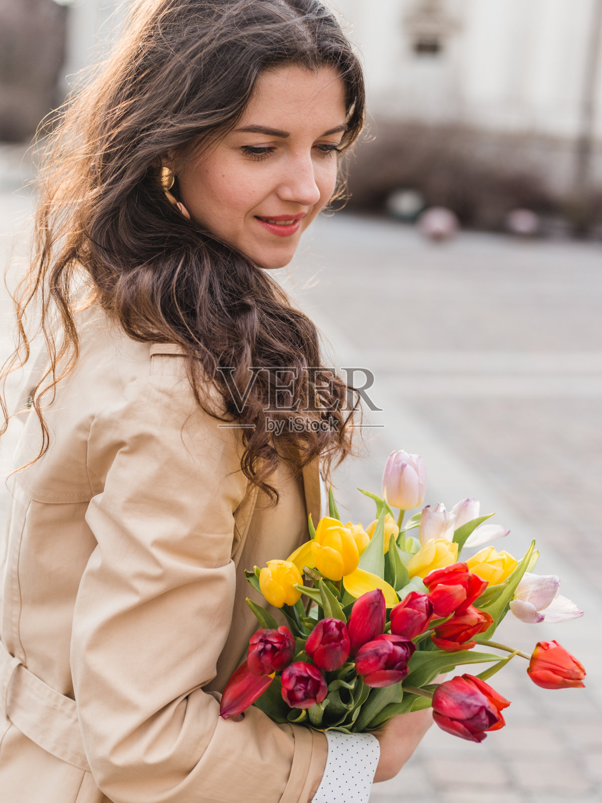 美丽的年轻女子与春天的郁金香鲜花在城市的街道。快乐的女孩在户外散步。旧城美女春照照片摄影图片