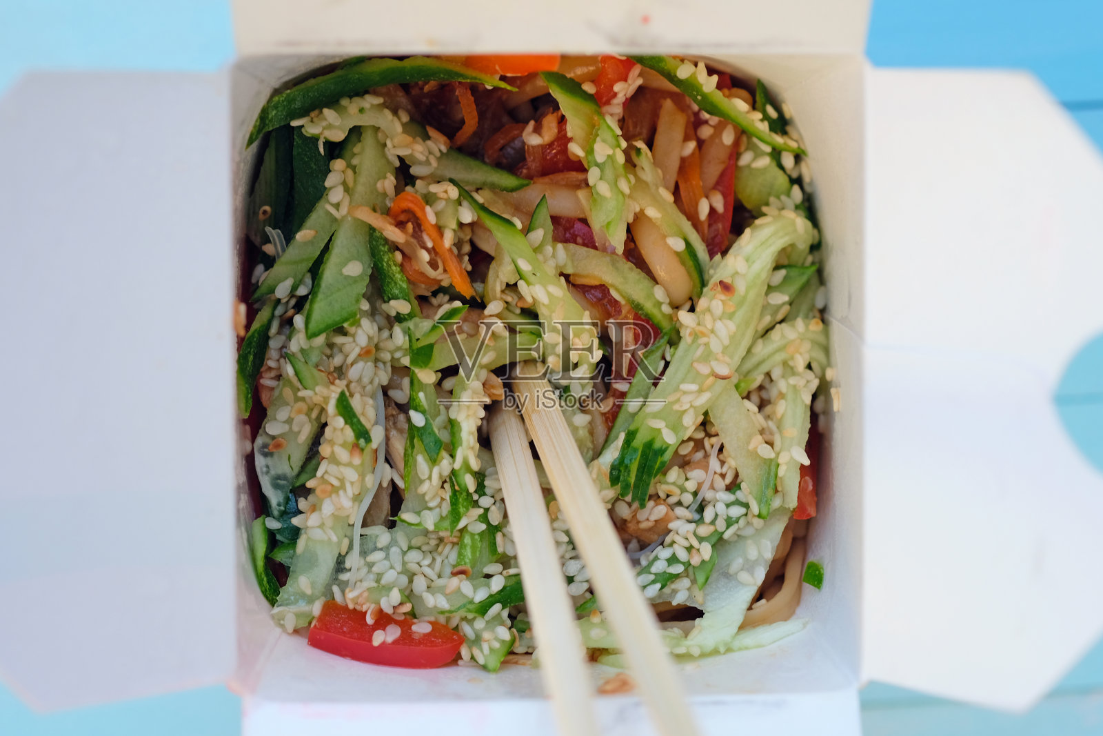 中国面条与蔬菜和肉撒芝麻在一个纸盒俯视图。照片摄影图片