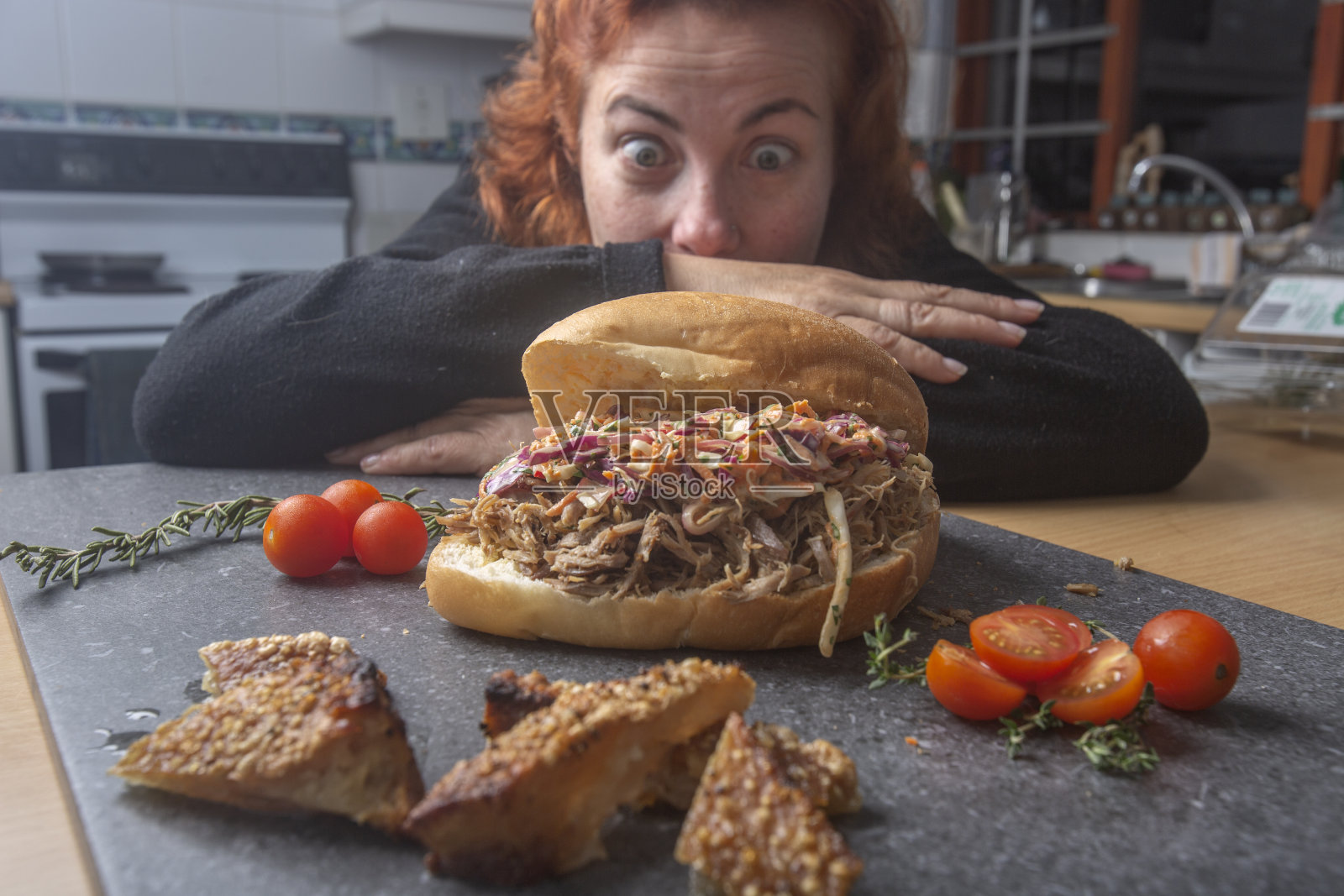 一个女人盯着厨房里的猪肉三明治照片摄影图片