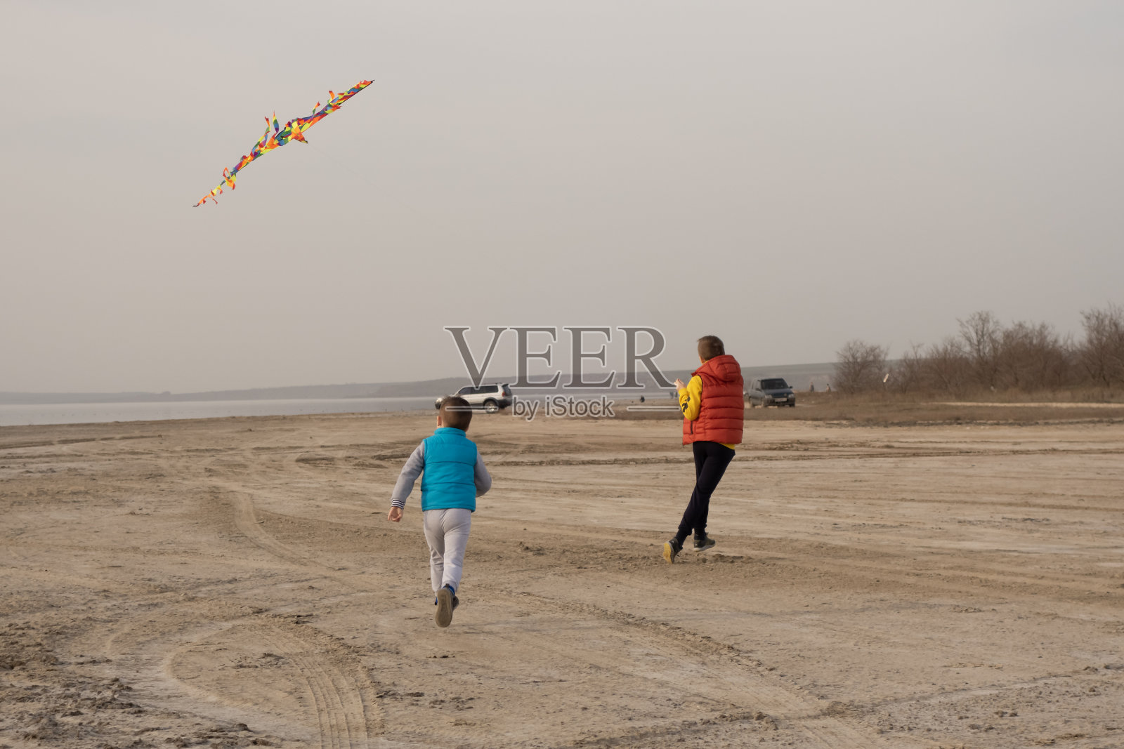 两个10岁和4岁的兄弟在空旷的海滩上玩耍。放风筝。照片摄影图片