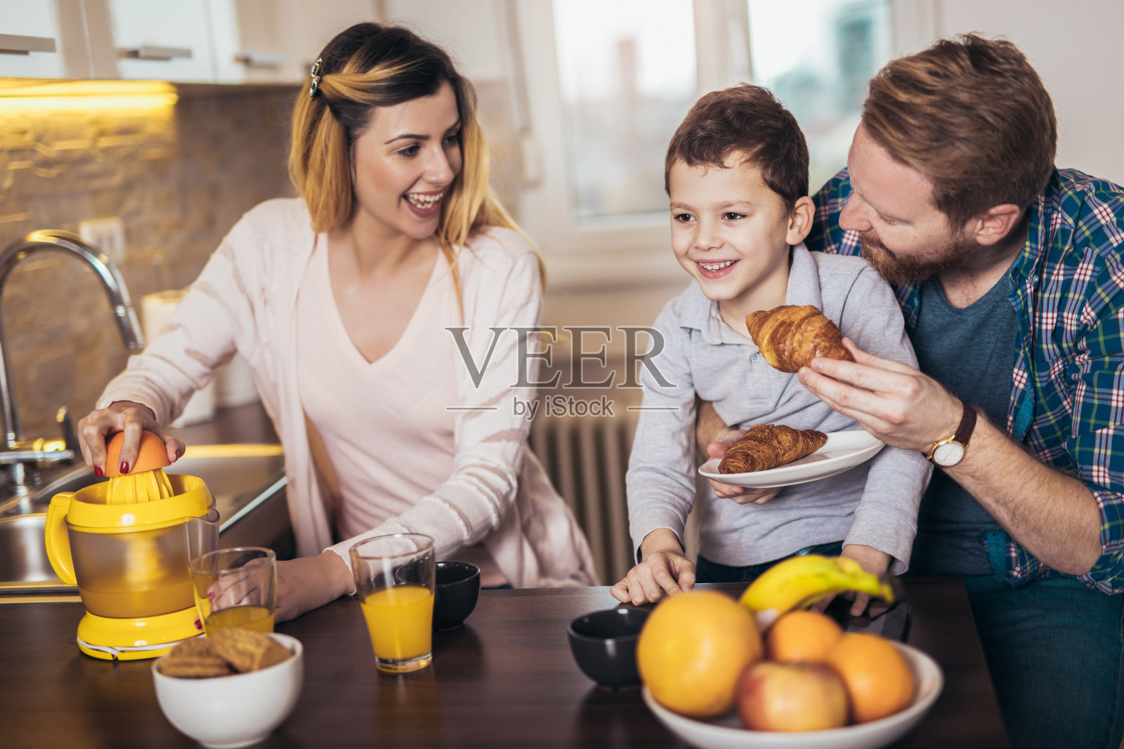 一个轻松快乐的家庭在厨房吃早餐，玩得很开心。照片摄影图片