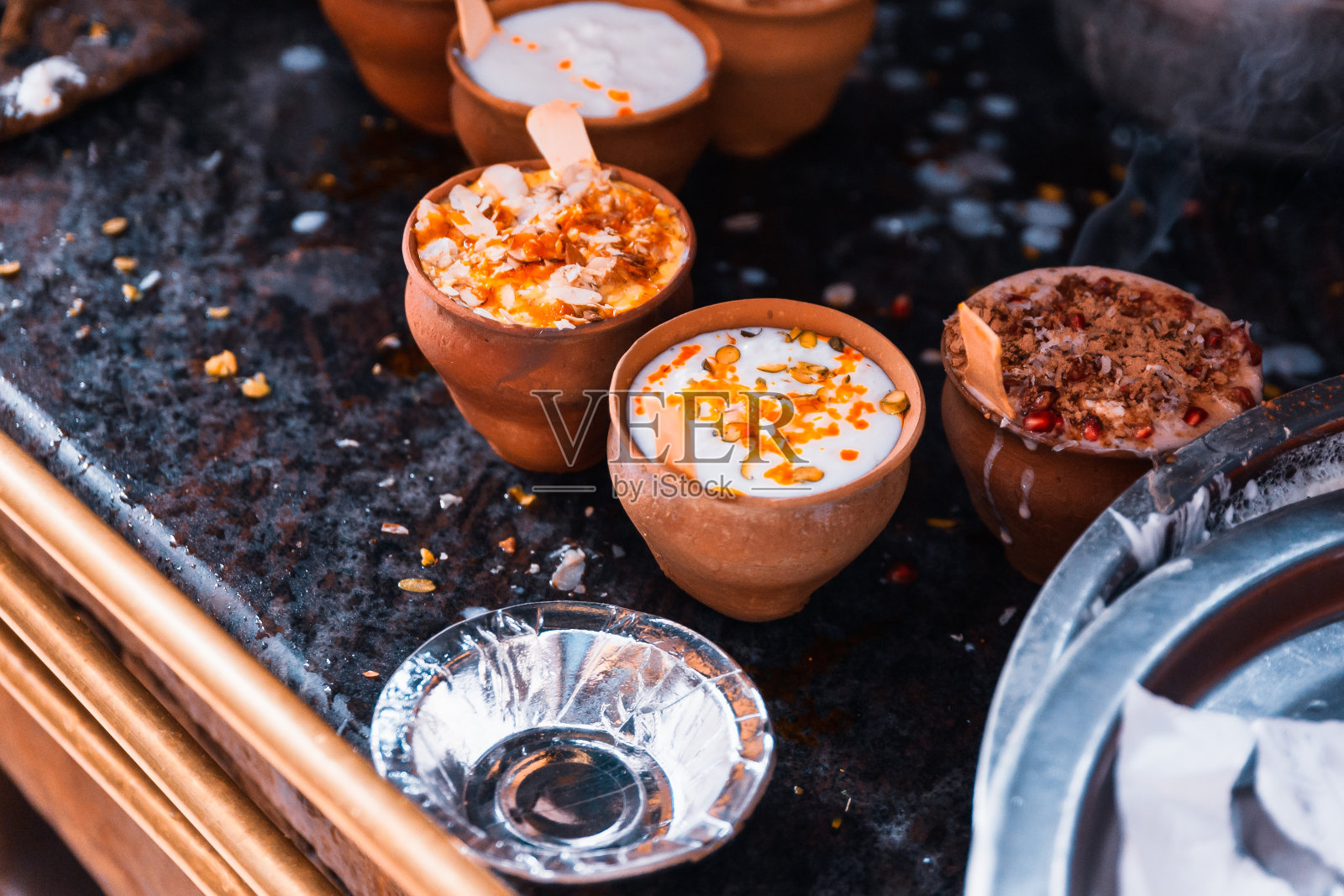 印度流行饮料lassi(传统达希酸奶饮料)在泥杯和各种各样的浇头在瓦拉纳西的街道上。照片摄影图片