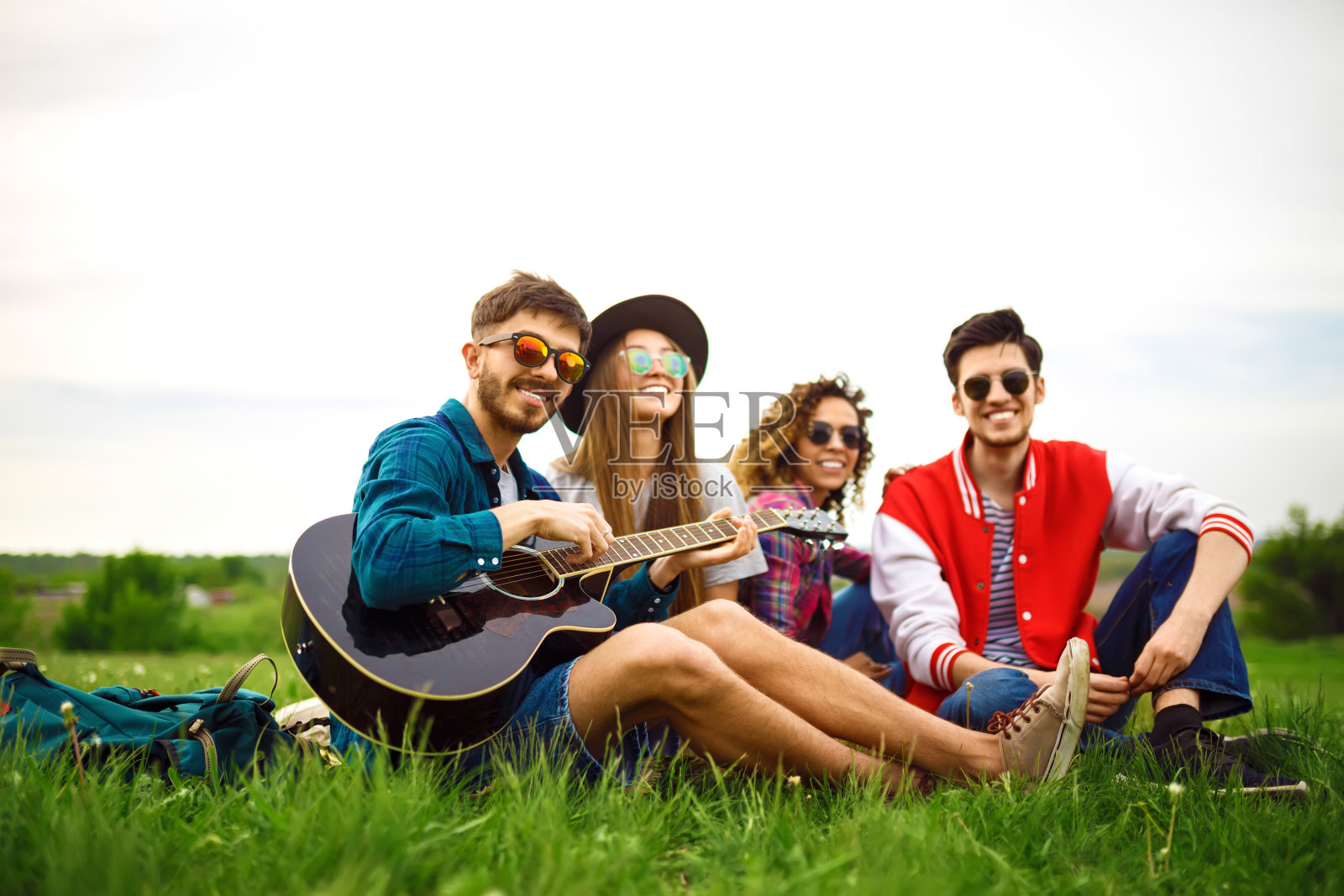 一群朋友在绿色草地上玩吉他。照片摄影图片