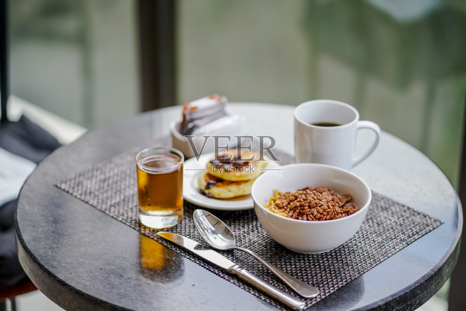 一套早餐:一碗麦片、煎饼、一杯咖啡和苹果汁。照片摄影图片