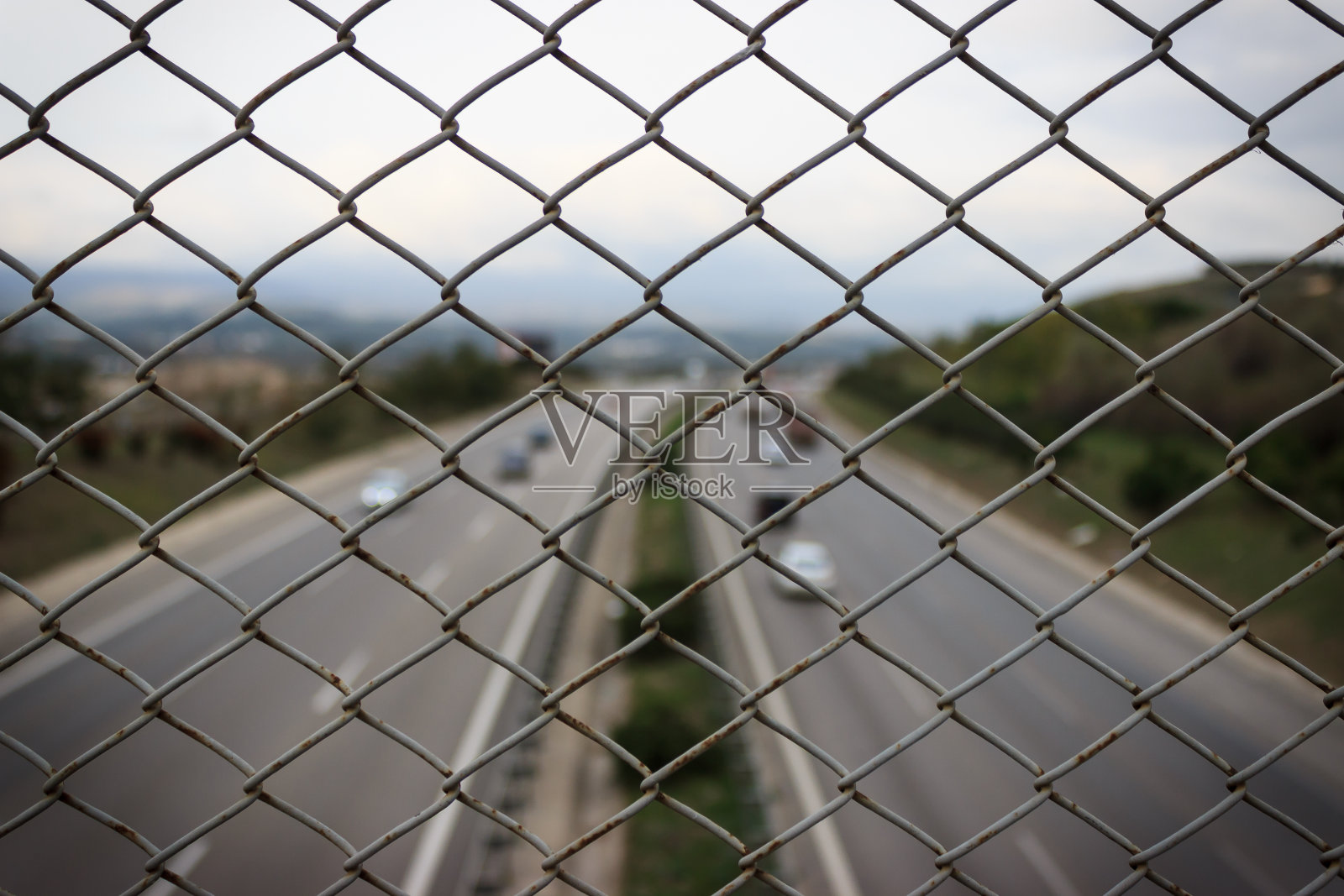 丝网围栏的闭合模式。公路景观和交通在道路上的背景。照片摄影图片