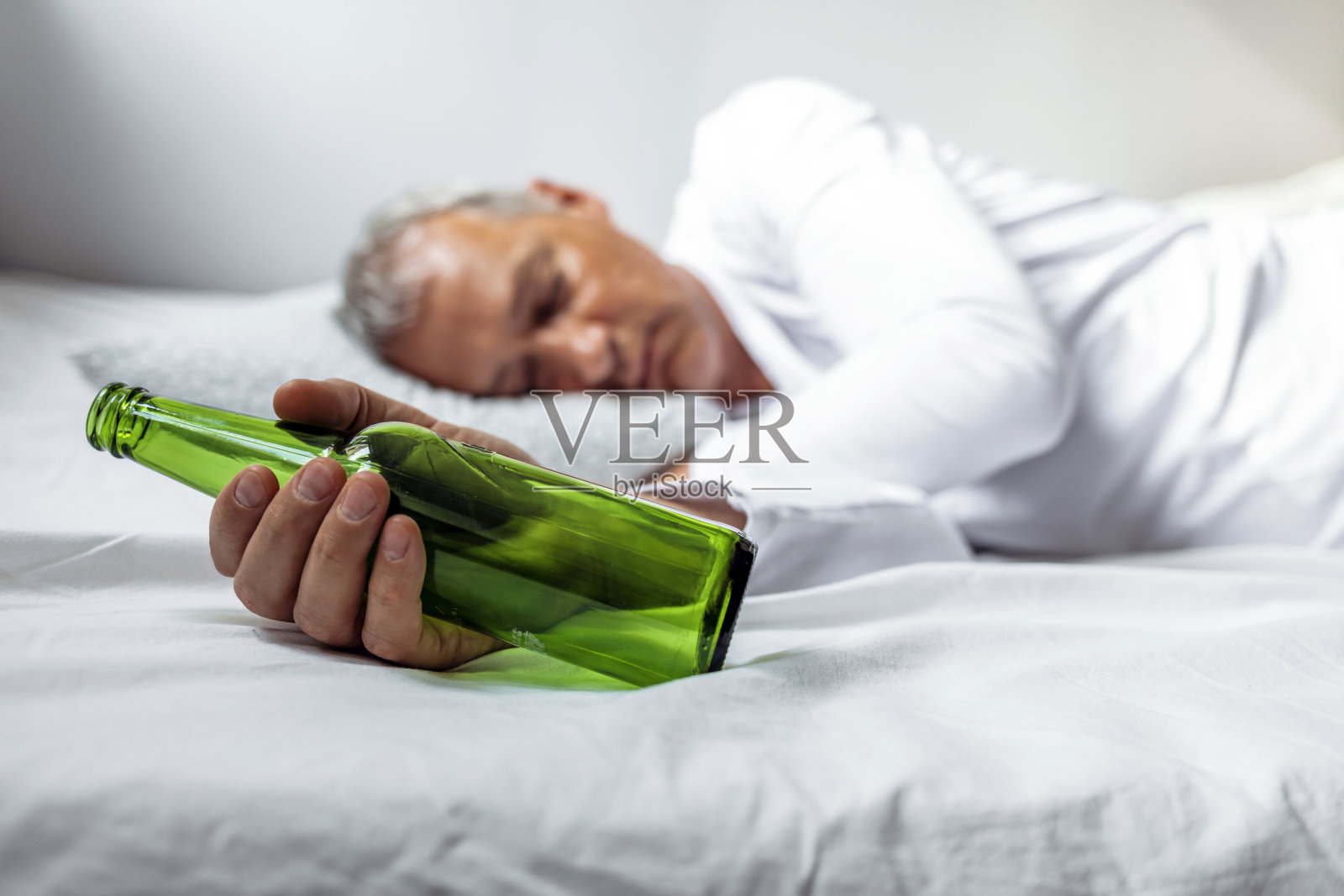 男人躺在家里的床上，饱受头痛和宿醉之苦照片摄影图片