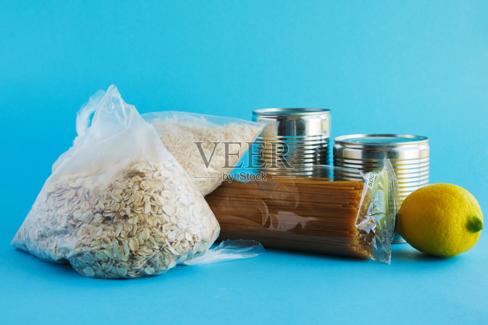 粮食援助,捐款。基本必需品，燕麦片，大米，意大利面，罐头食品，蓝色背景上的蔬菜。照片摄影图片
