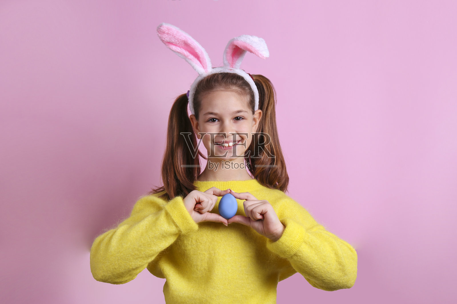 一个女孩戴着兔子耳朵庆祝复活节的概念形象。照片摄影图片