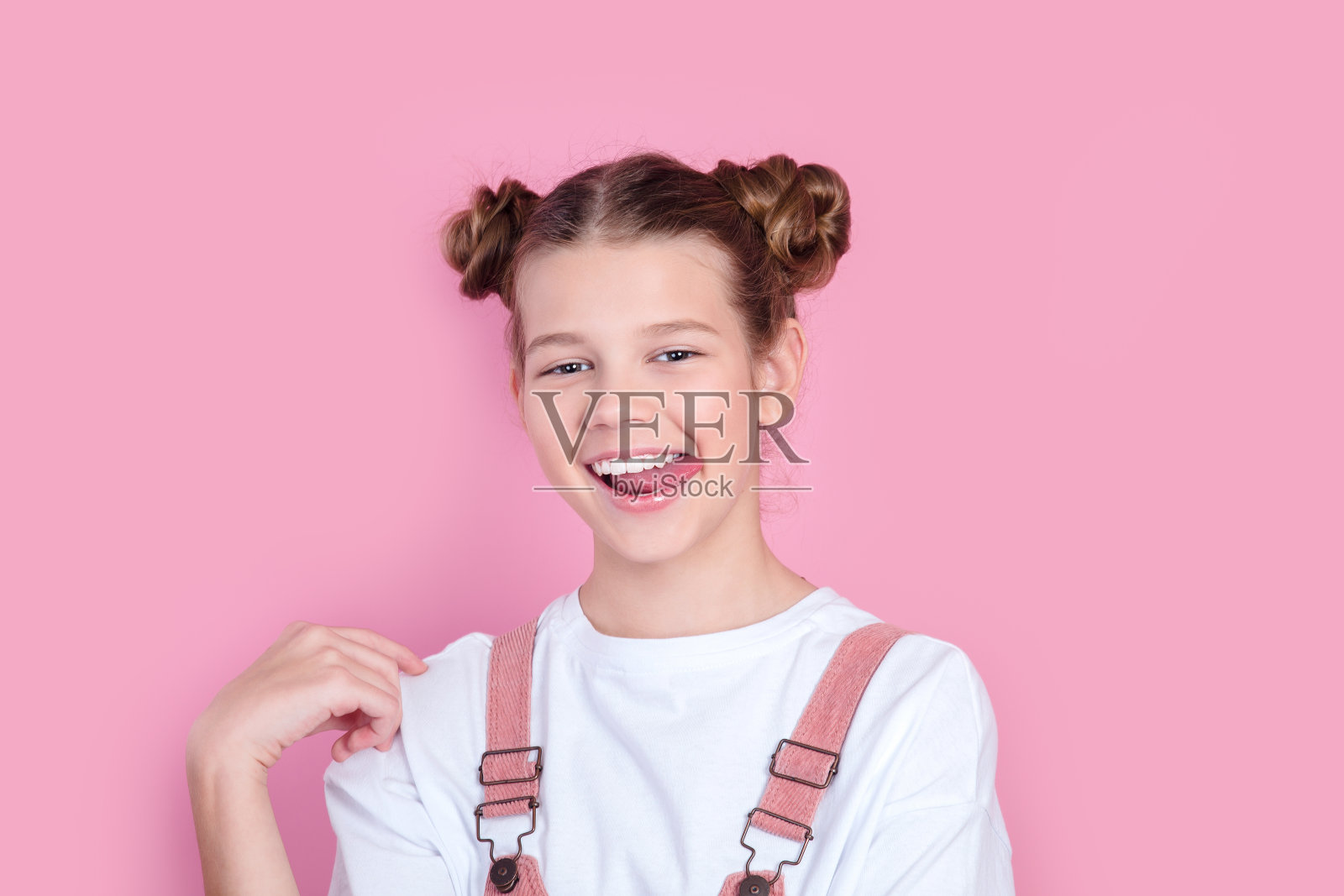 笑着的年轻女孩在粉红色的背景下露出她的舌头照片摄影图片
