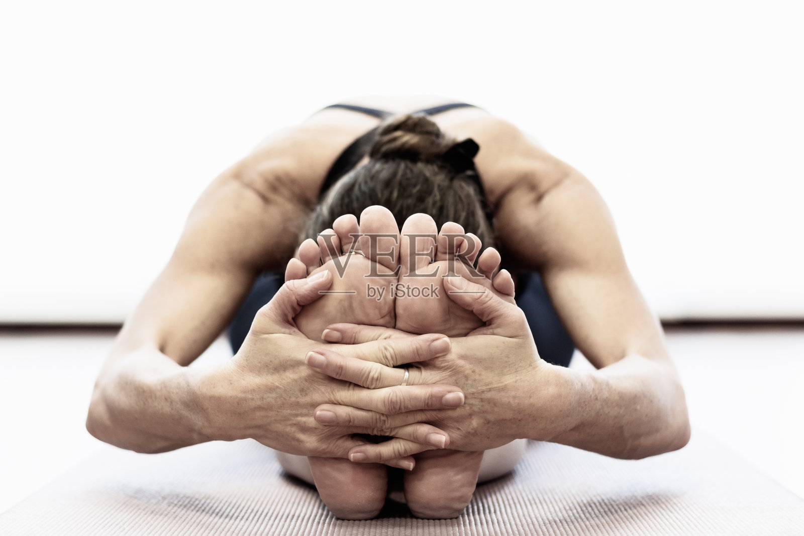 特写上的女人的手坐前弯体式抓脚在光明瑜伽工作室照片摄影图片