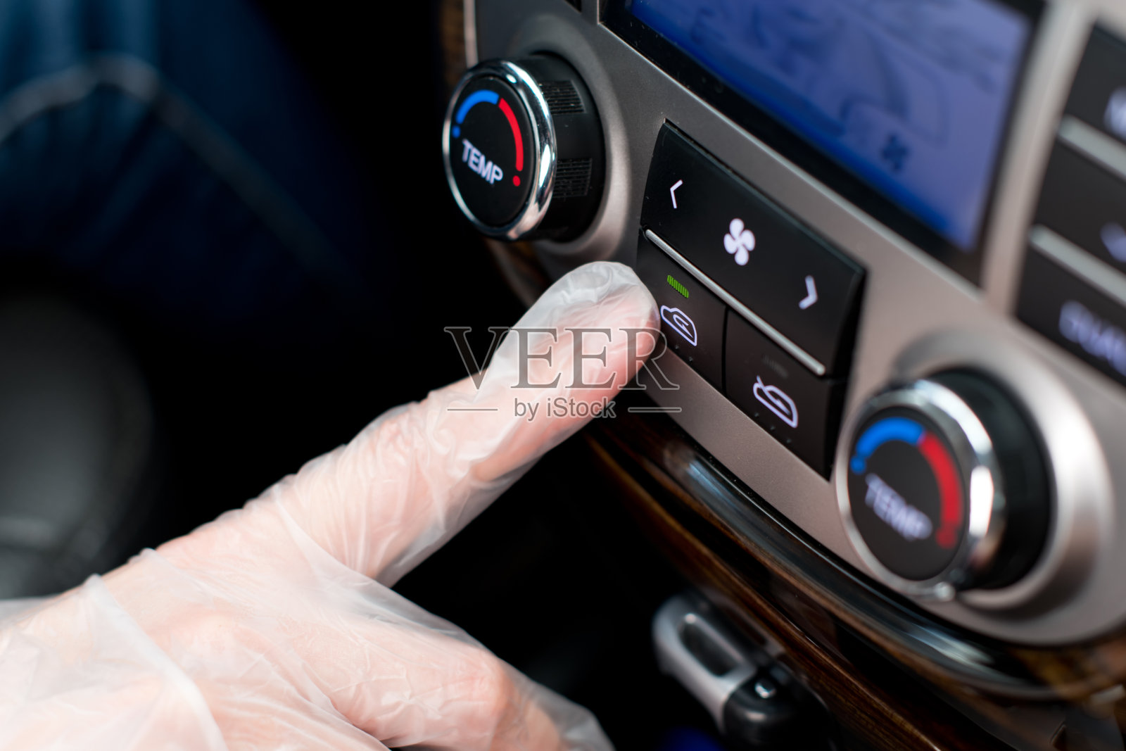 一只戴着医用手套的手按下了车里的空气再循环按钮照片摄影图片