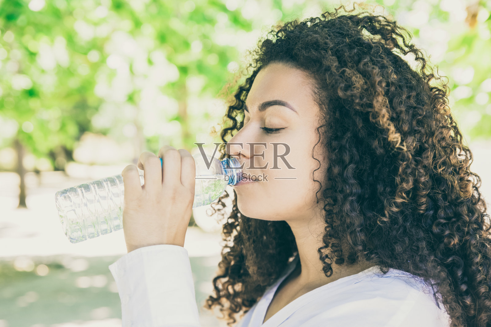 美丽的卷发女人喝水照片摄影图片