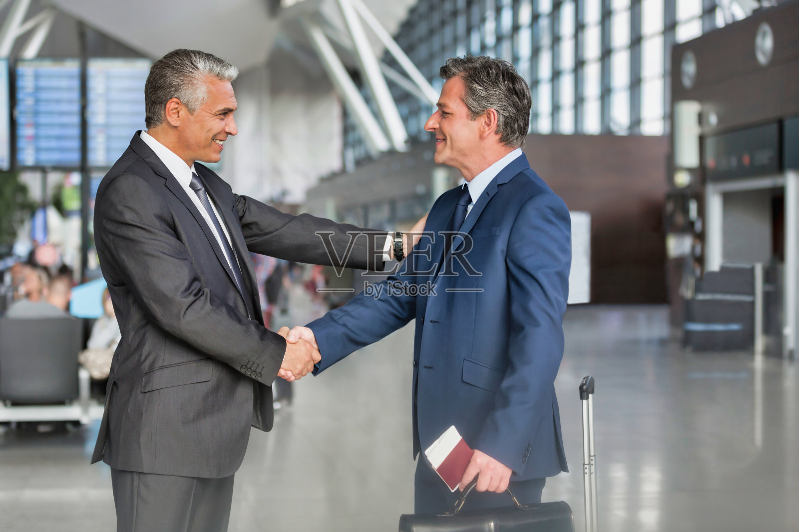 成熟的商人在机场与商业伙伴握手照片摄影图片