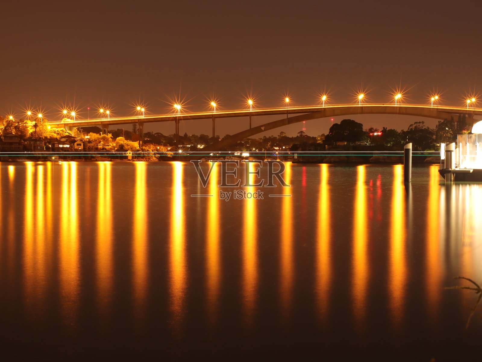 在澳大利亚悉尼的格拉迪斯维尔大桥被明亮的灯光和平静的港口水域照亮照片摄影图片