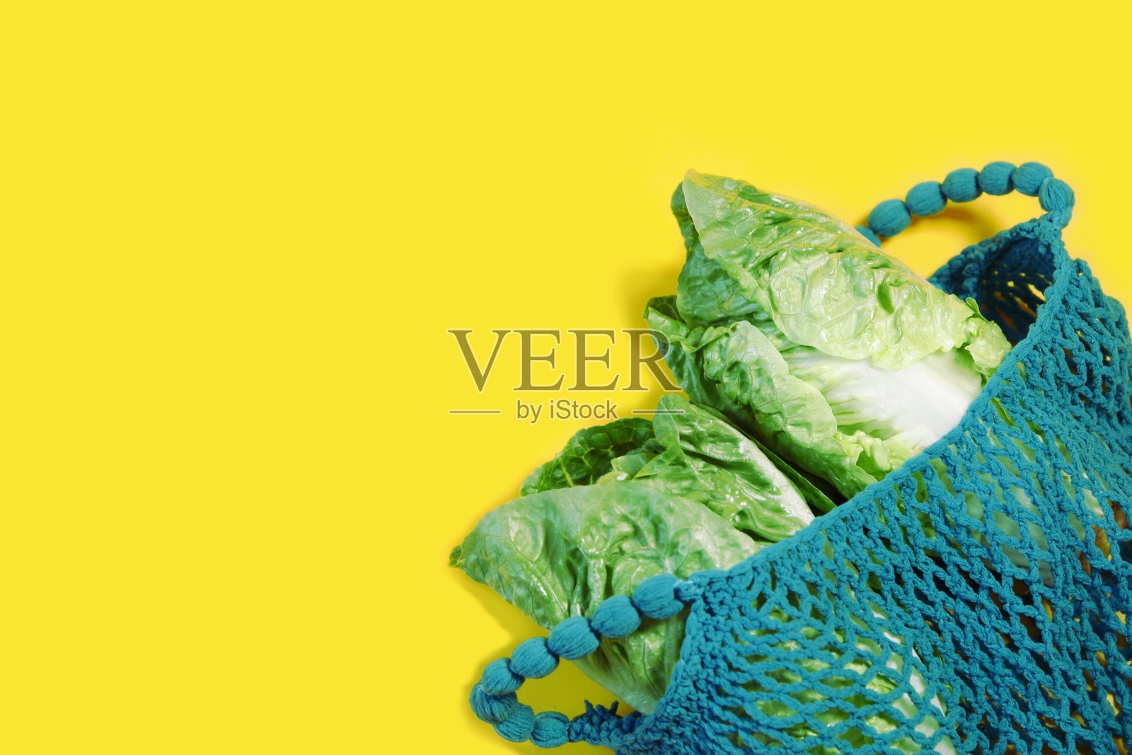 可重复使用的购物网袋，开放的网袋与绿色罗马生菜沙拉，莴苣在黄色的背景。零浪费，环保购物和生态理念。塑料免费照片摄影图片