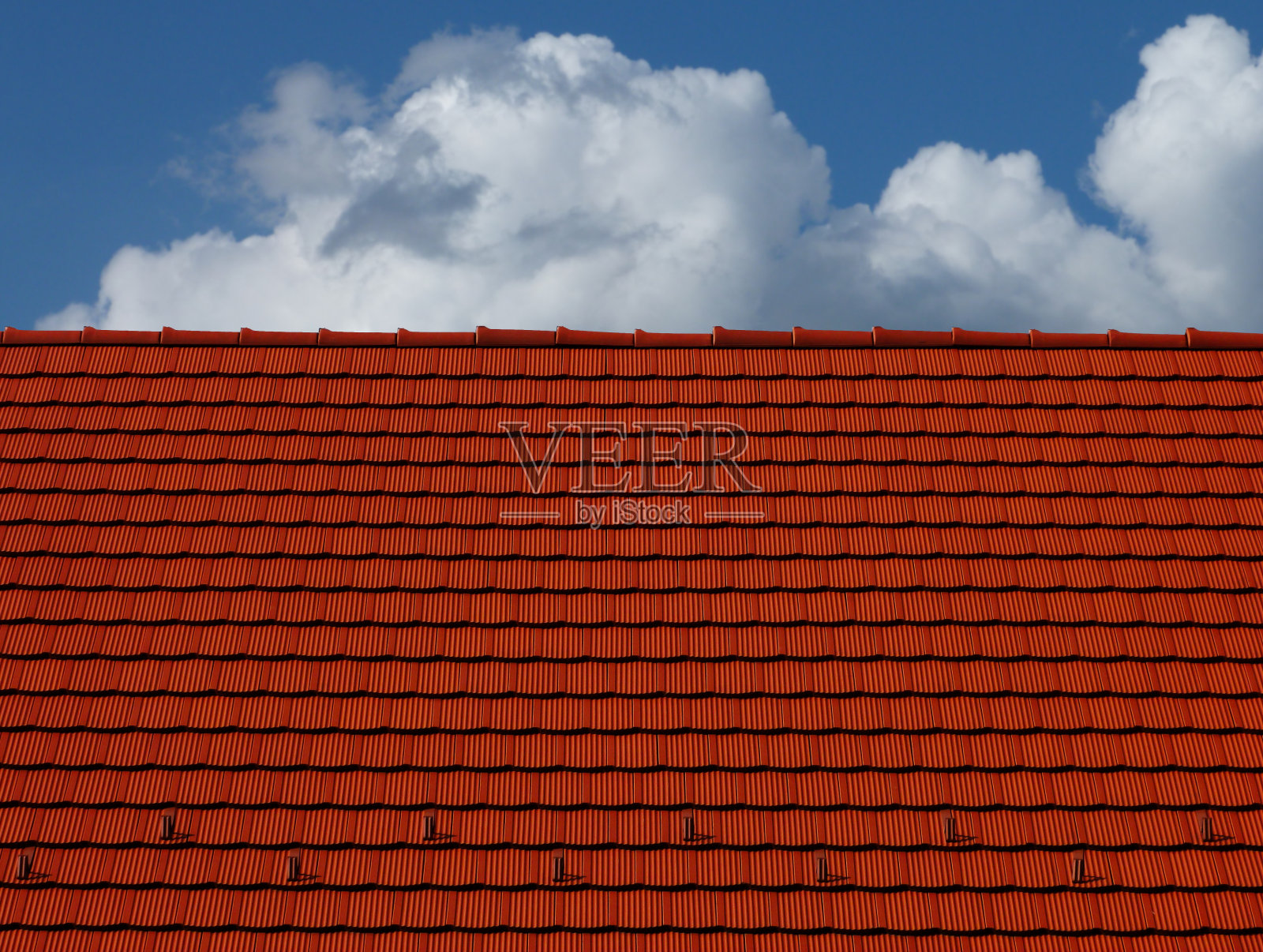 红粘土瓦屋顶和屋脊。白云和蓝天照片摄影图片