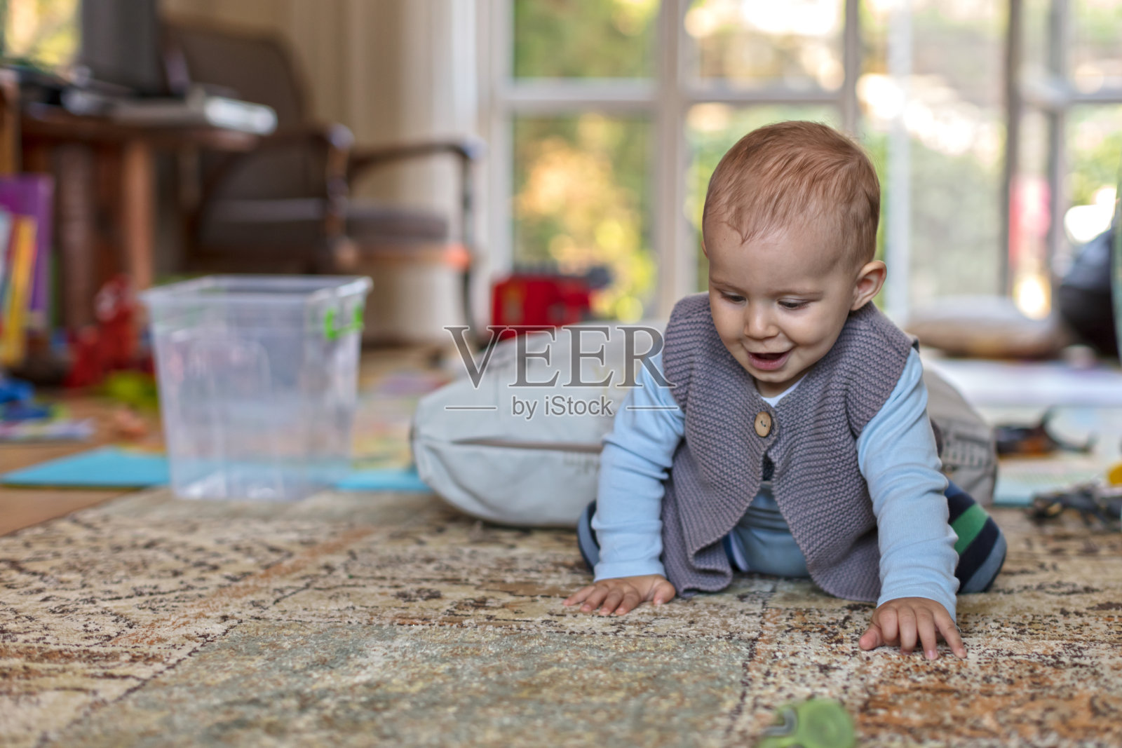 小男孩和一个玩具在家里的地板上爬照片摄影图片