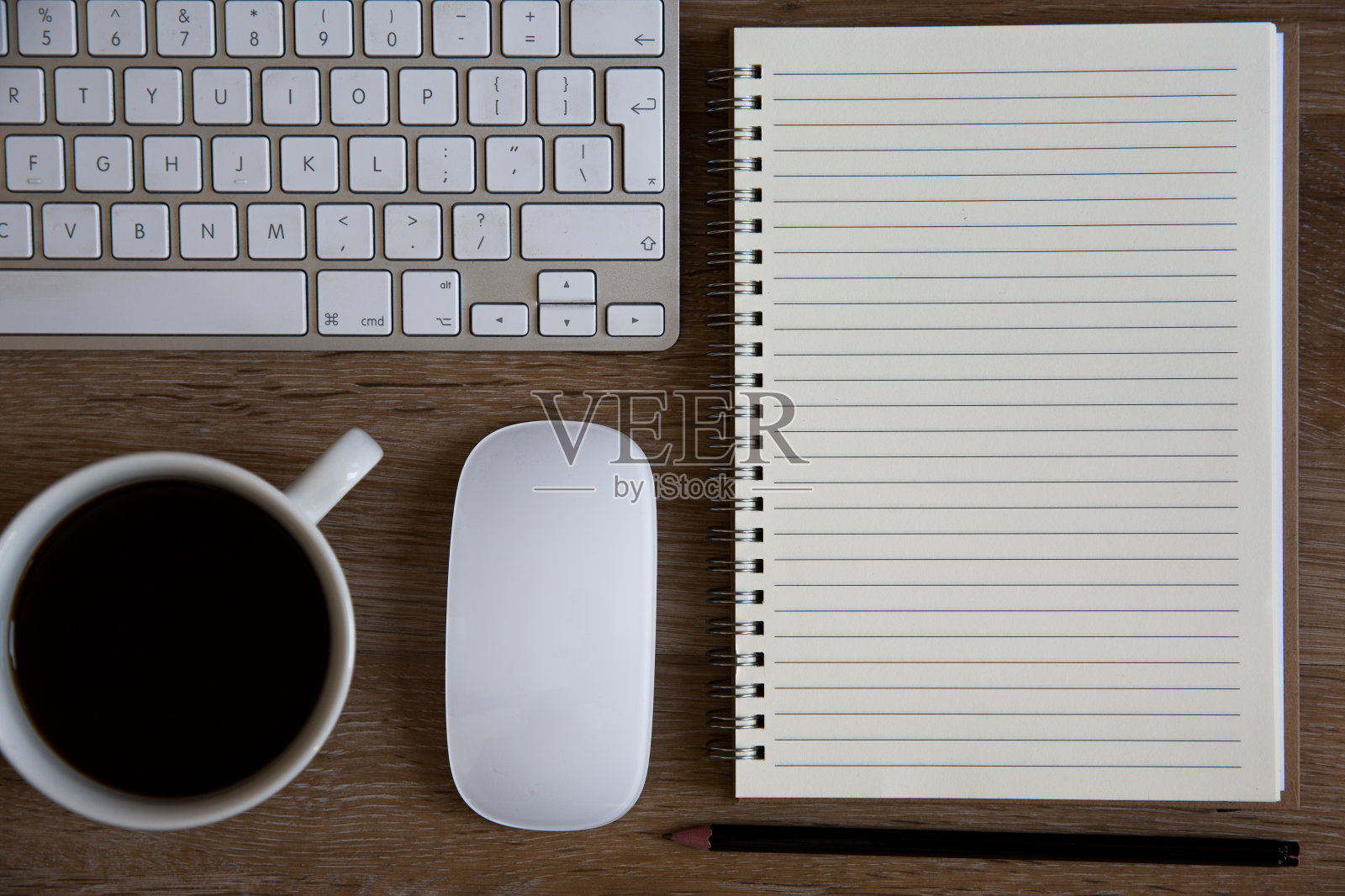 一个复古桌面或家庭办公室的高角度视图，有咖啡杯、键盘、鼠标和螺旋笔记本，有空白页用于笔记和复制空间照片摄影图片