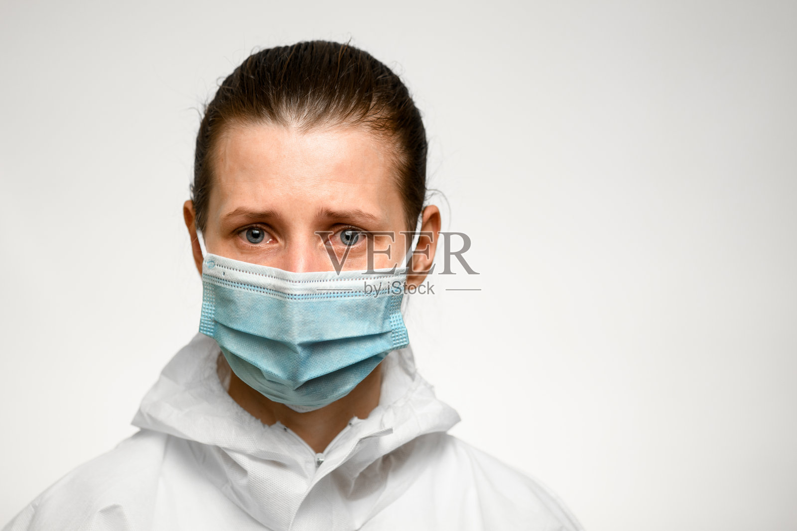 蓝眼睛和悲伤表情的妇女戴着预防流感的医用口罩。照片摄影图片