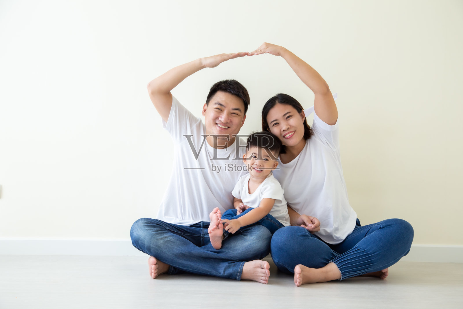 爸爸和妈妈双手捂着头做屋顶图，亚洲家庭和儿子坐在房间的地板上，新建筑住宅购买公寓的概念照片摄影图片