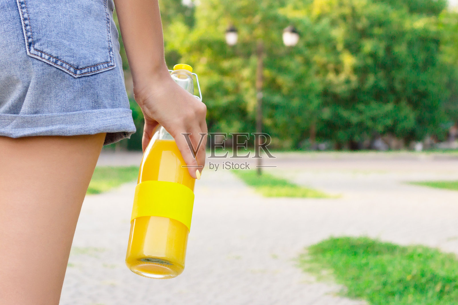 一个美丽的女孩拿着一瓶新鲜的果汁或柠檬水在外面裁剪的图像照片摄影图片